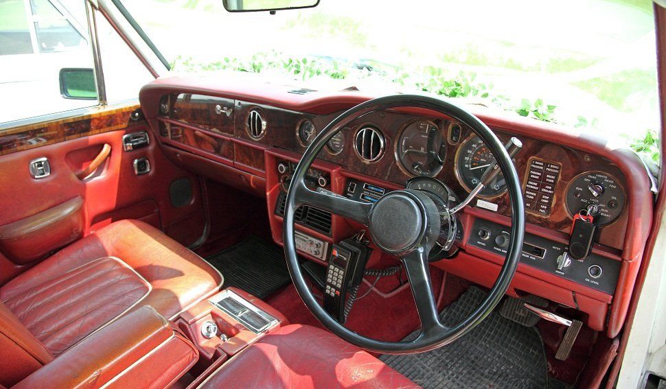 The interior of a car, furnished in wood and red leather