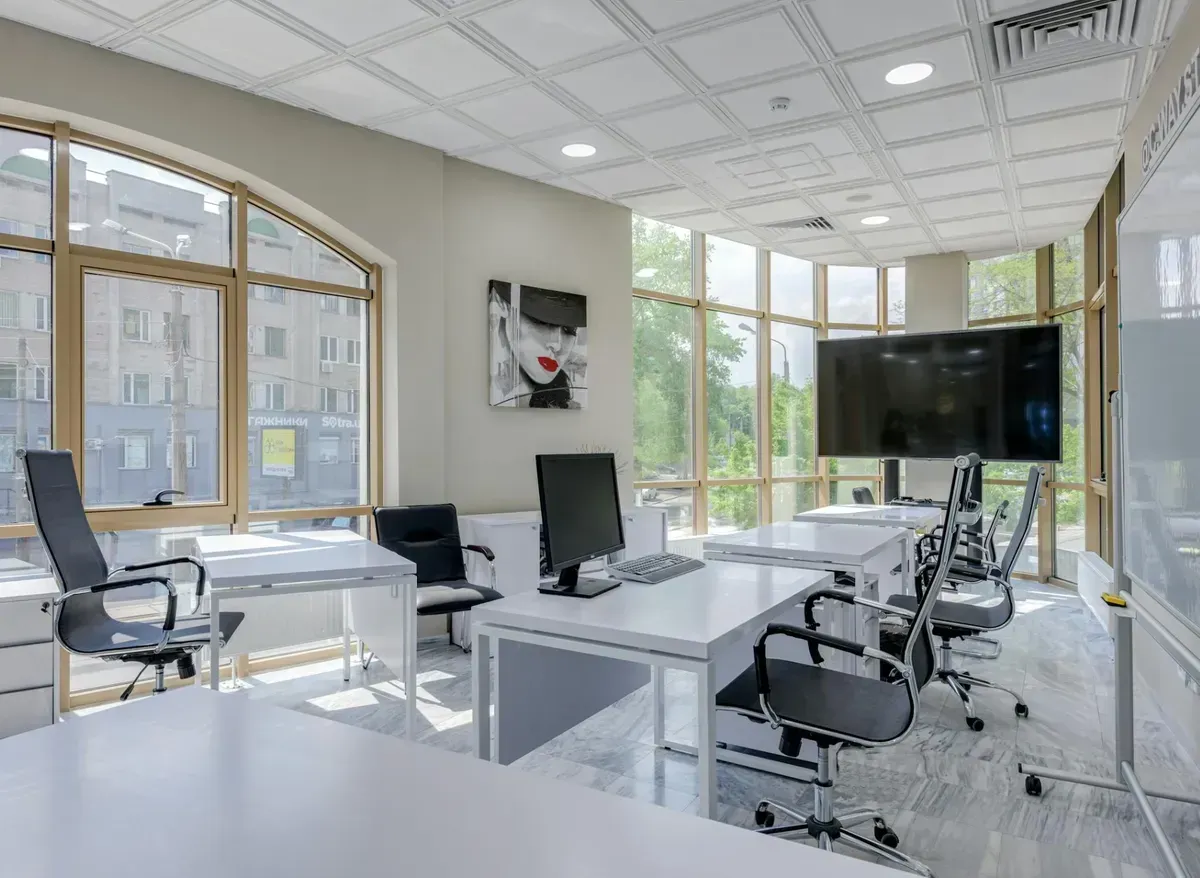 A large room with lots of windows and tables and chairs.