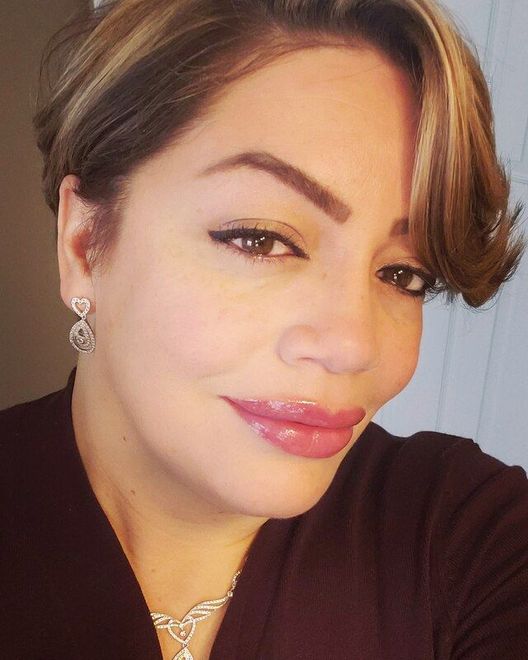 A close up of a woman 's face wearing earrings and a necklace