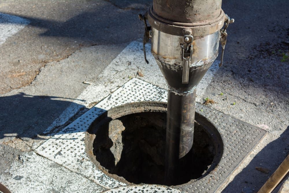 Open Manhole With a Vertical Pipe Descending Into a Dark Street Opening — Mark's Plumbing in The Entrance, NSW