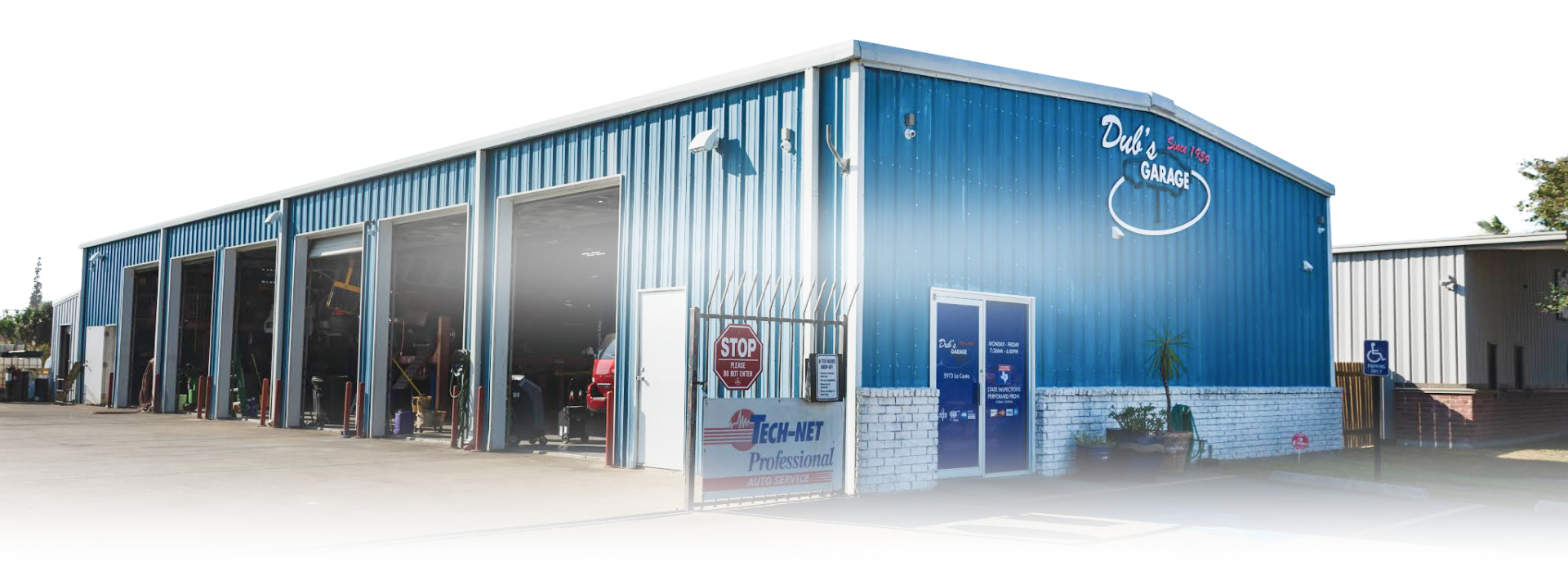Blue industrial building with large garage doors and storefront windows on a street corner | Dub's Garage