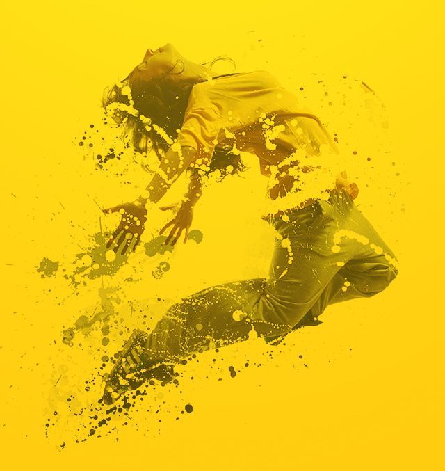 Man with a beard and arms crossed, wearing a light gray t-shirt, standing in a gym.