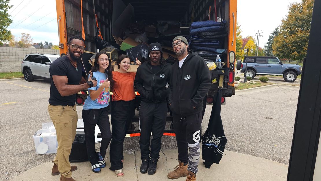 A group of people are posing for a picture in front of a truck.