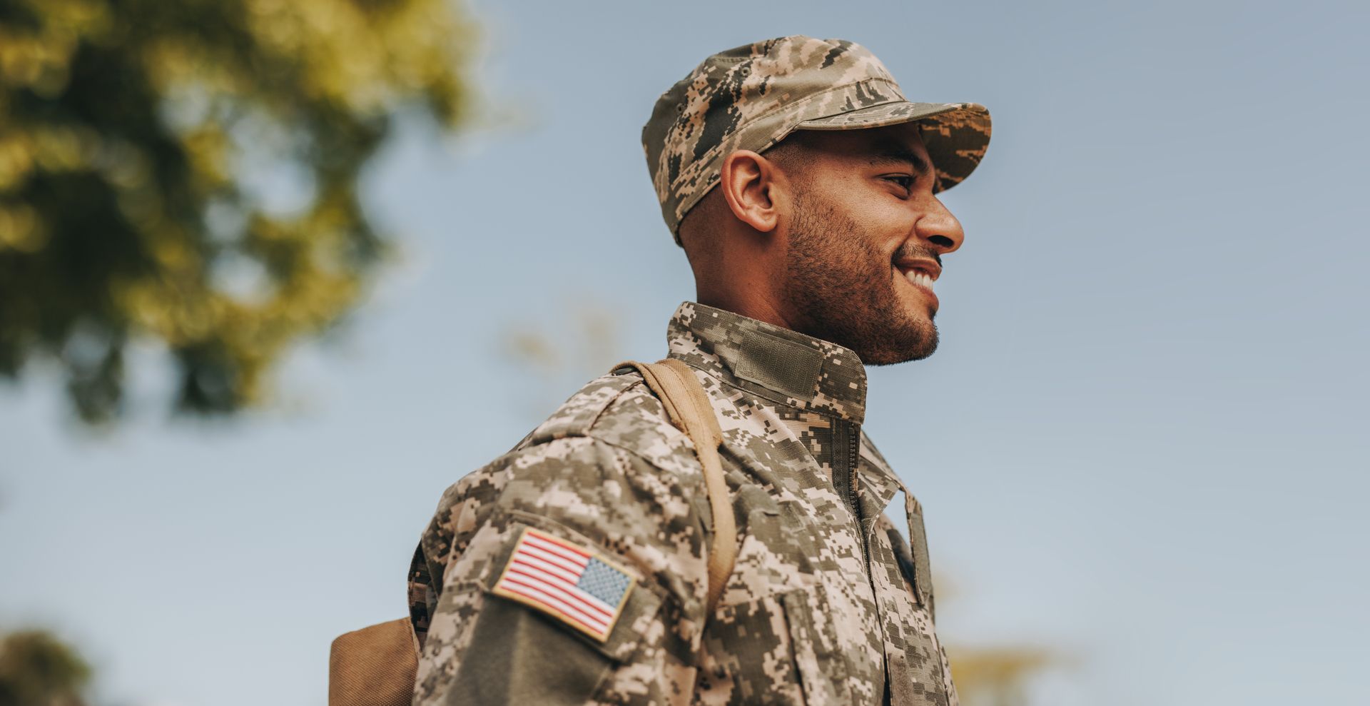 A man in a military uniform is walking with a backpack.