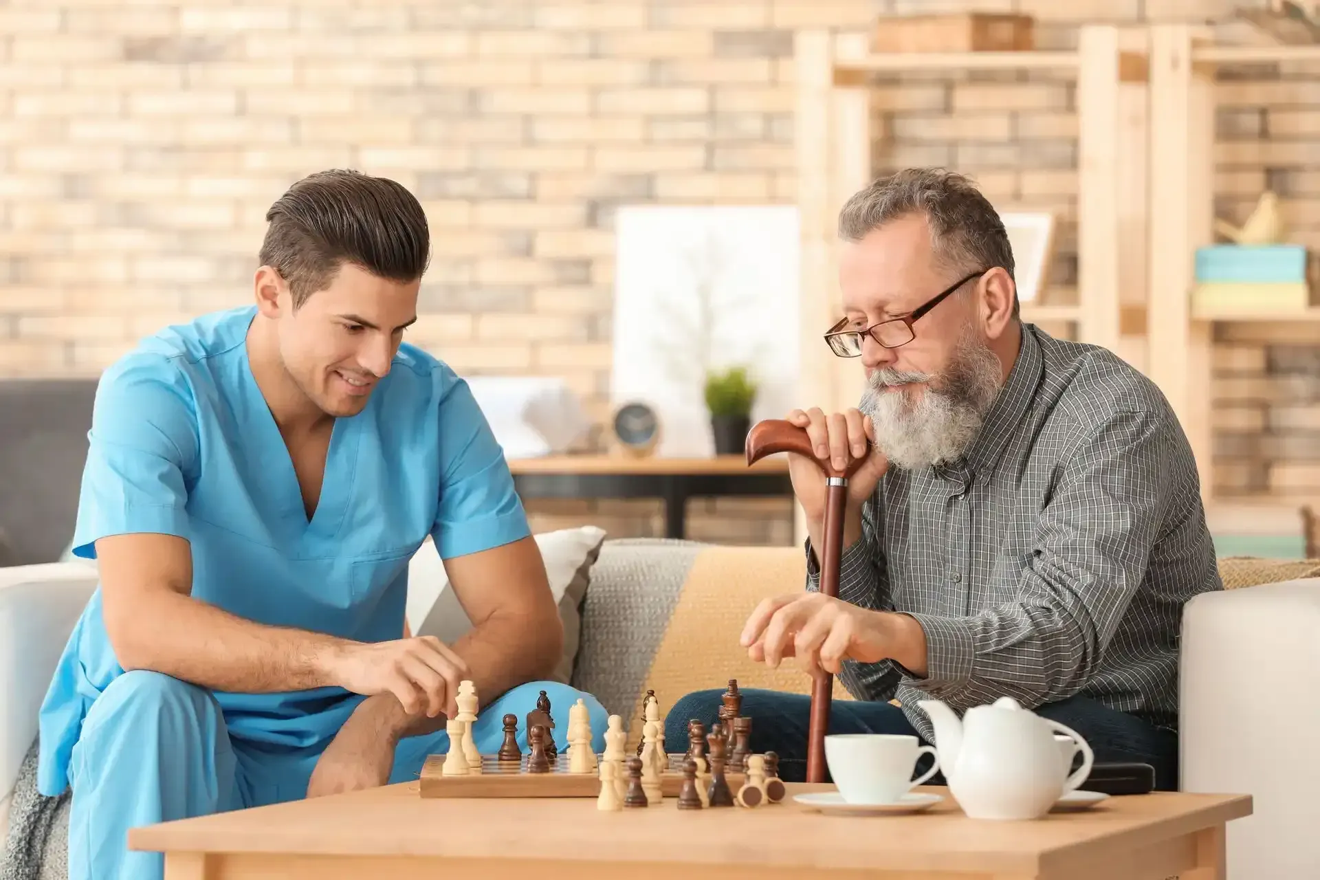 a nurse is teaching an elderly man how to play chess .