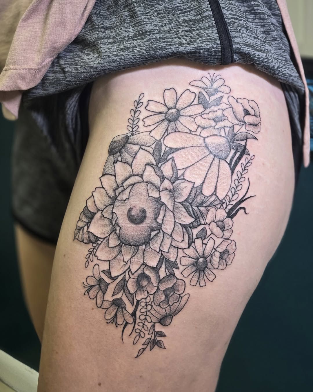 Black and white floral tattoo on a person's thigh.