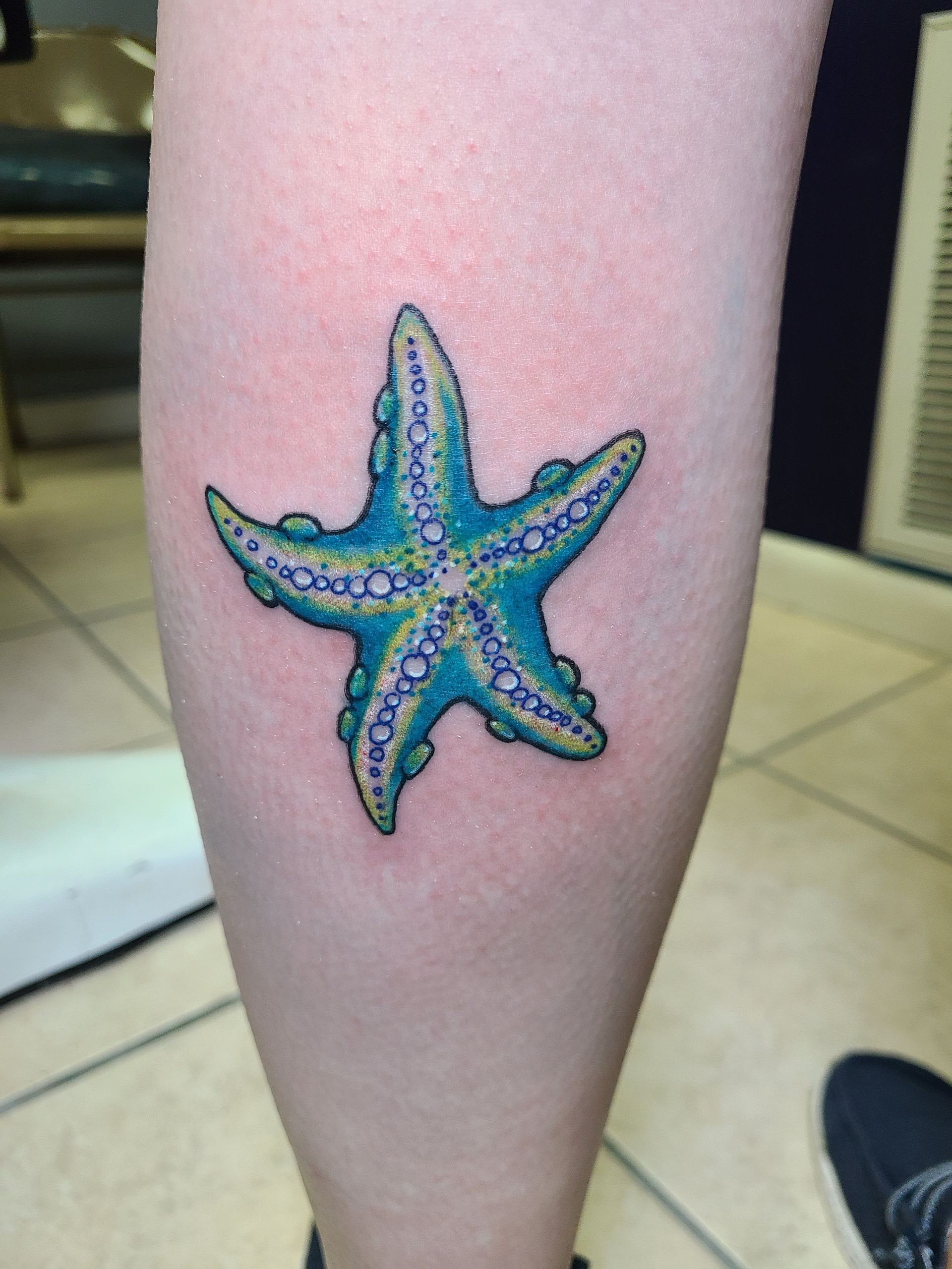 A blue starfish tattoo on a person 's leg