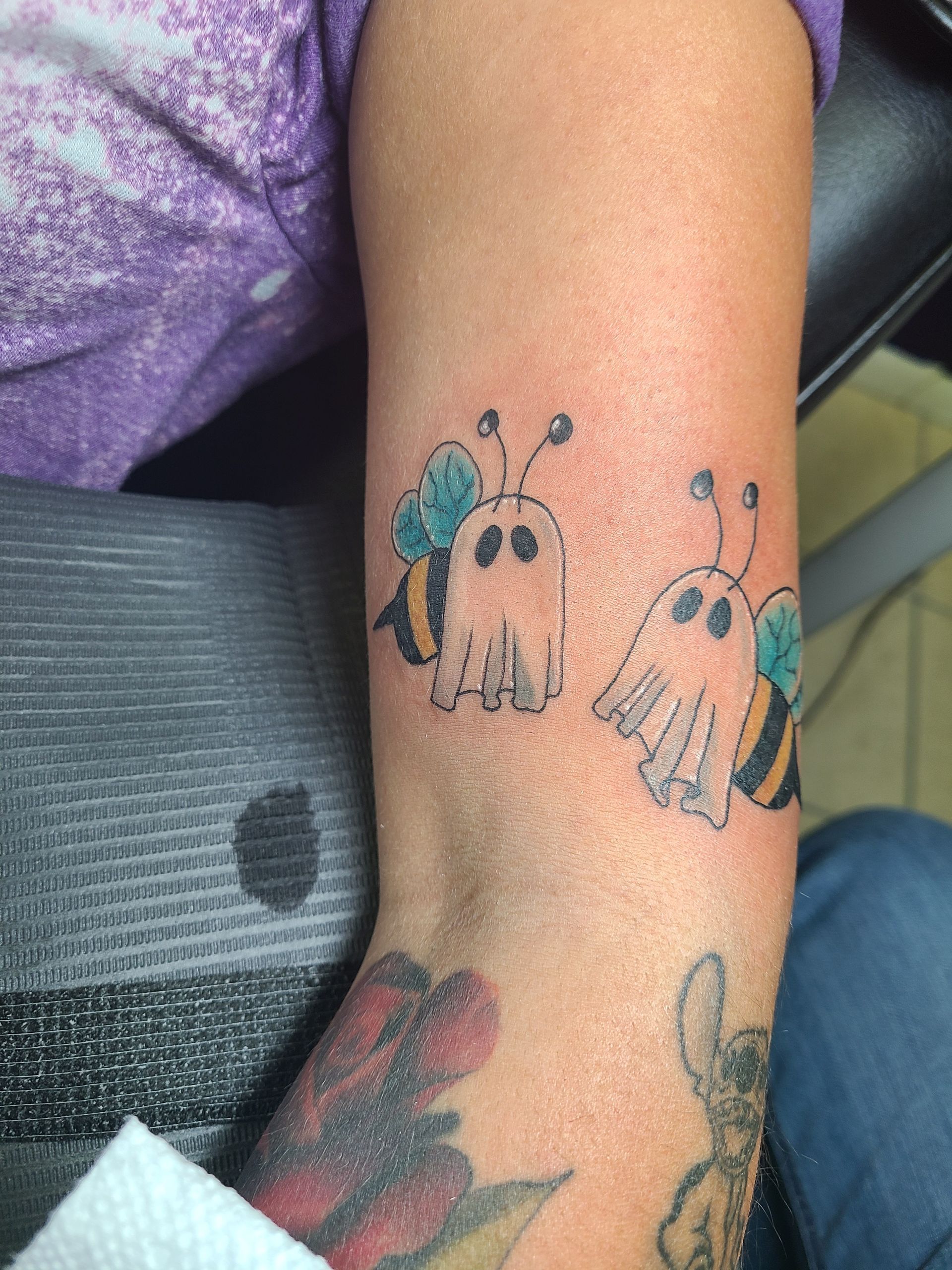 A woman has a tattoo of two bees on her arm.