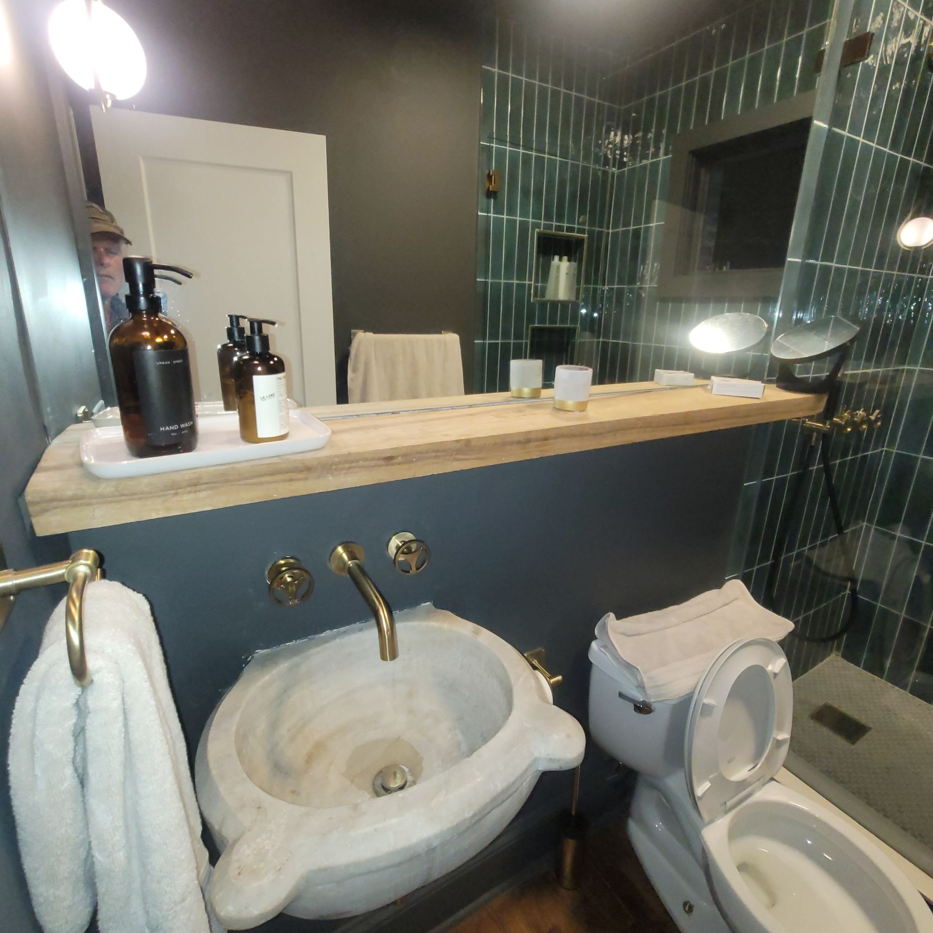 Bathroom with marble sink, gold fixtures, toiletries, and toilet.