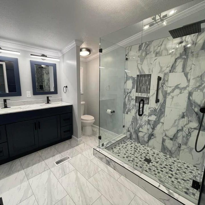 Office waiting room with gray couch, teal chairs, wood desk, and art on walls.