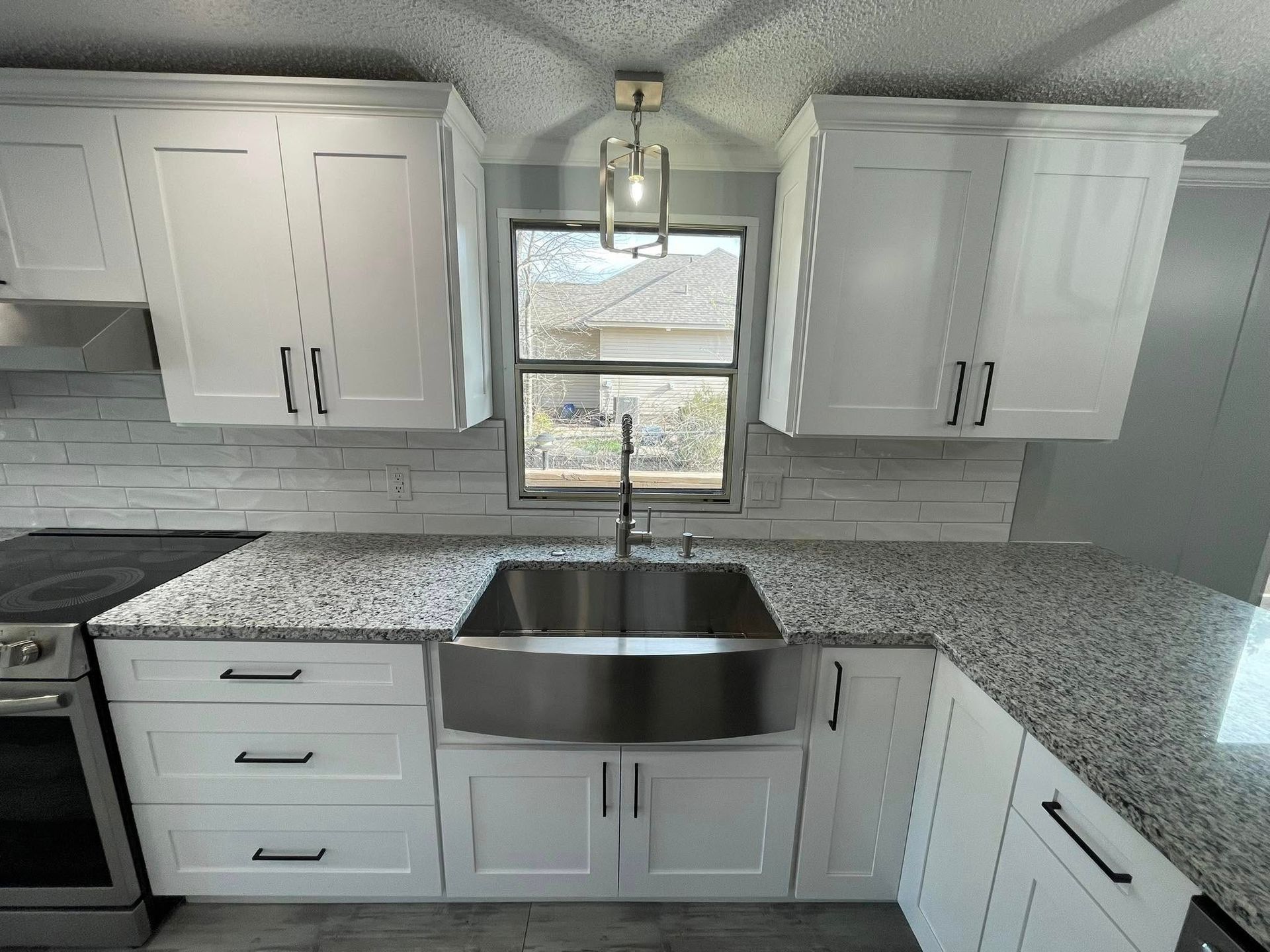 White kitchen with stainless steel sink, white cabinets, and granite countertops.