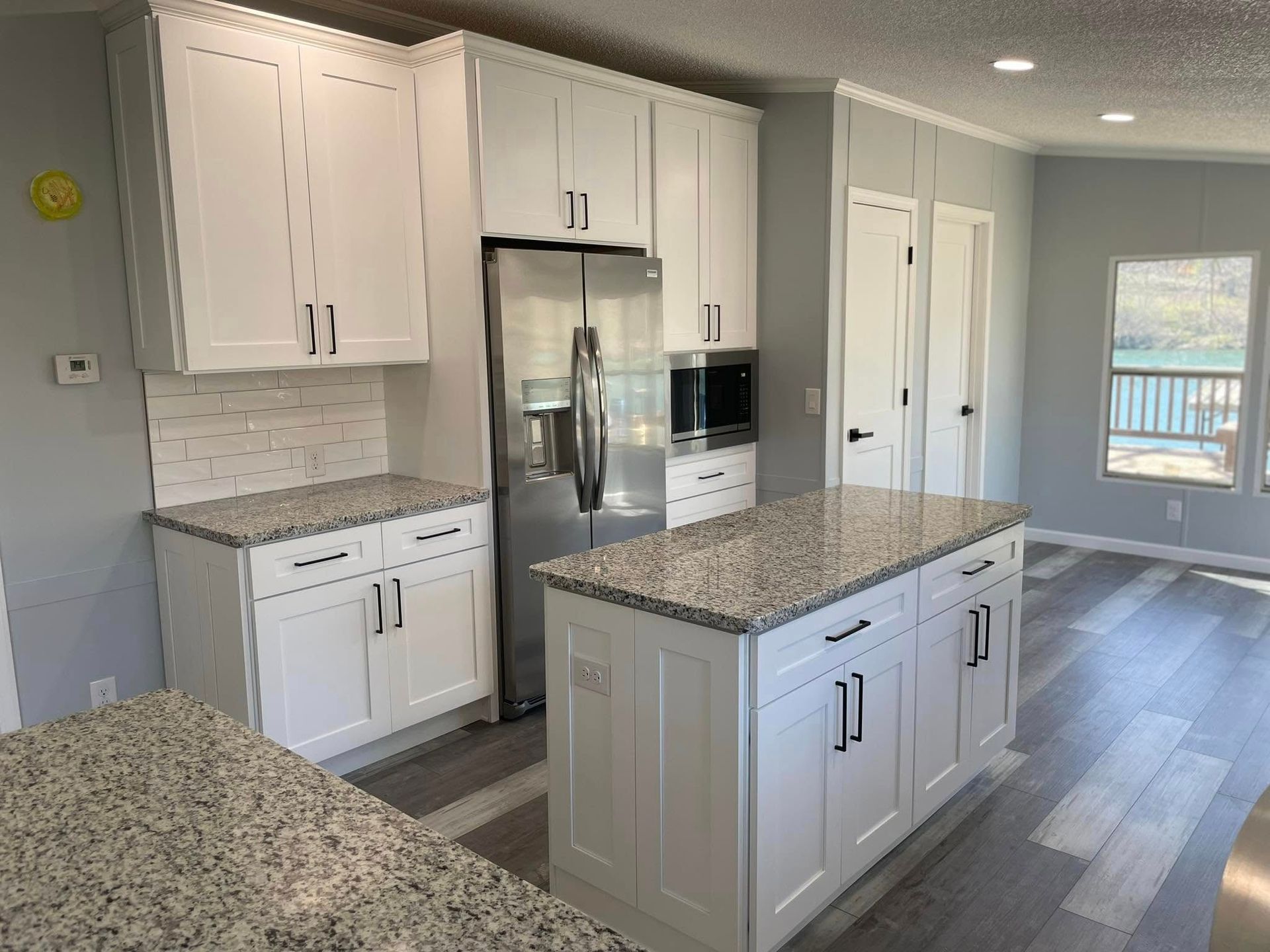 White kitchen with granite countertops, stainless steel appliances, and an island.