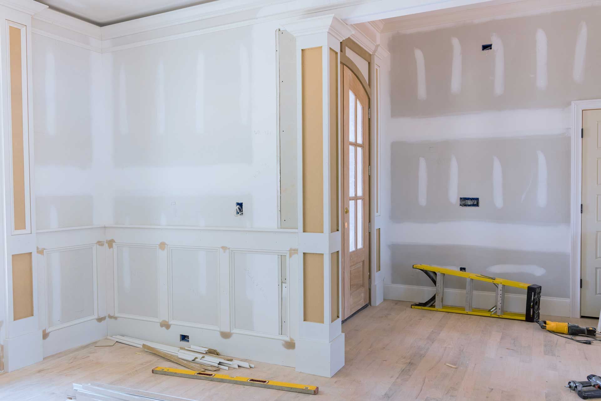 Interior room under construction, with drywall, trim, and wooden flooring.