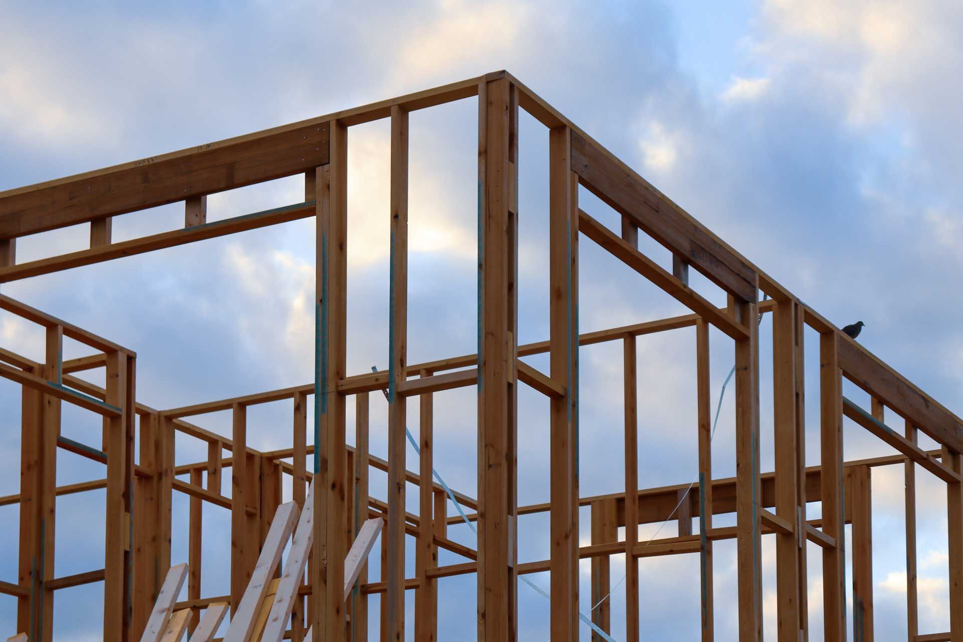 Wooden house frame against a cloudy sky, in the early stages of construction.