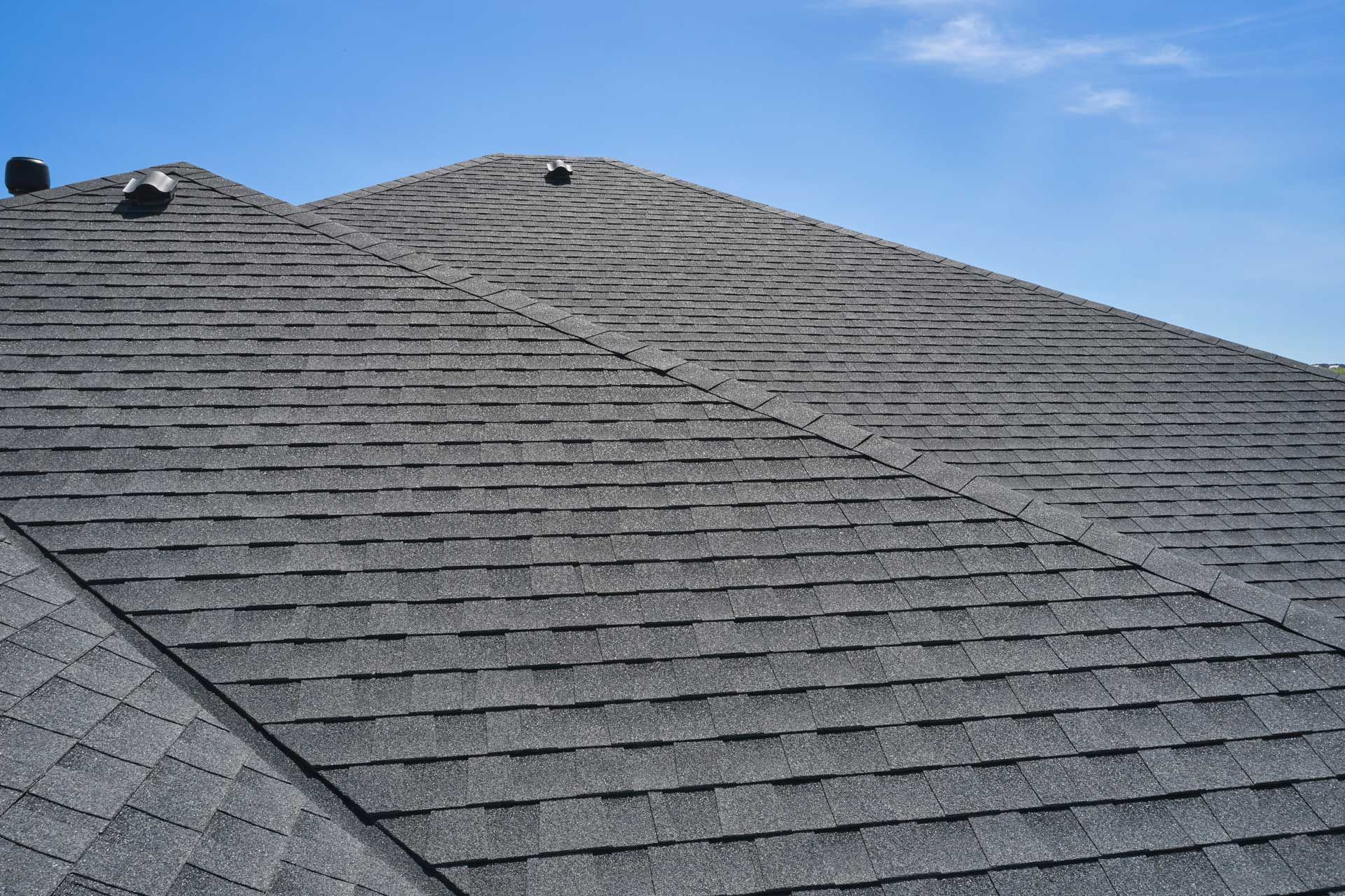 Partially re-roofed house with new plywood on the left, and old asphalt shingles on the right.