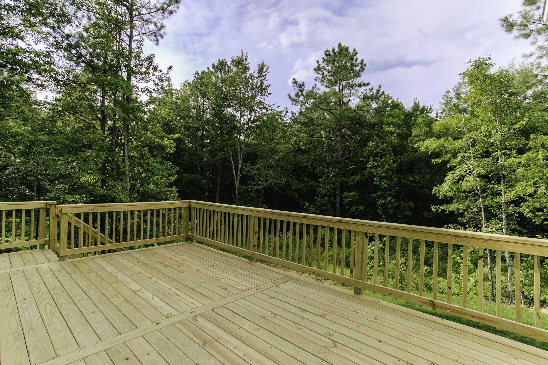 Wooden deck overlooking a forest of green trees under a cloudy sky.