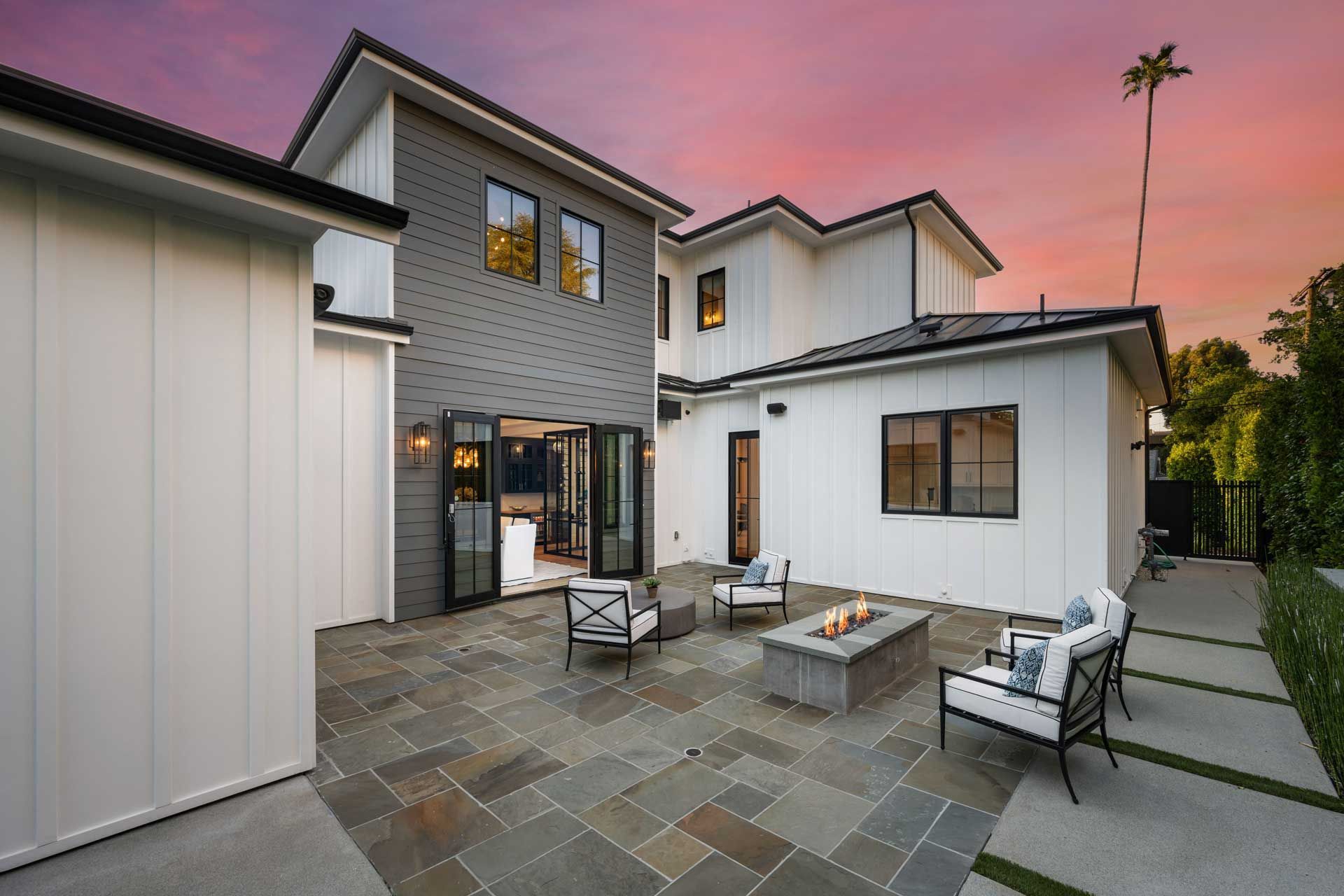 Modern home exterior with stone accents, gray siding, and large windows.