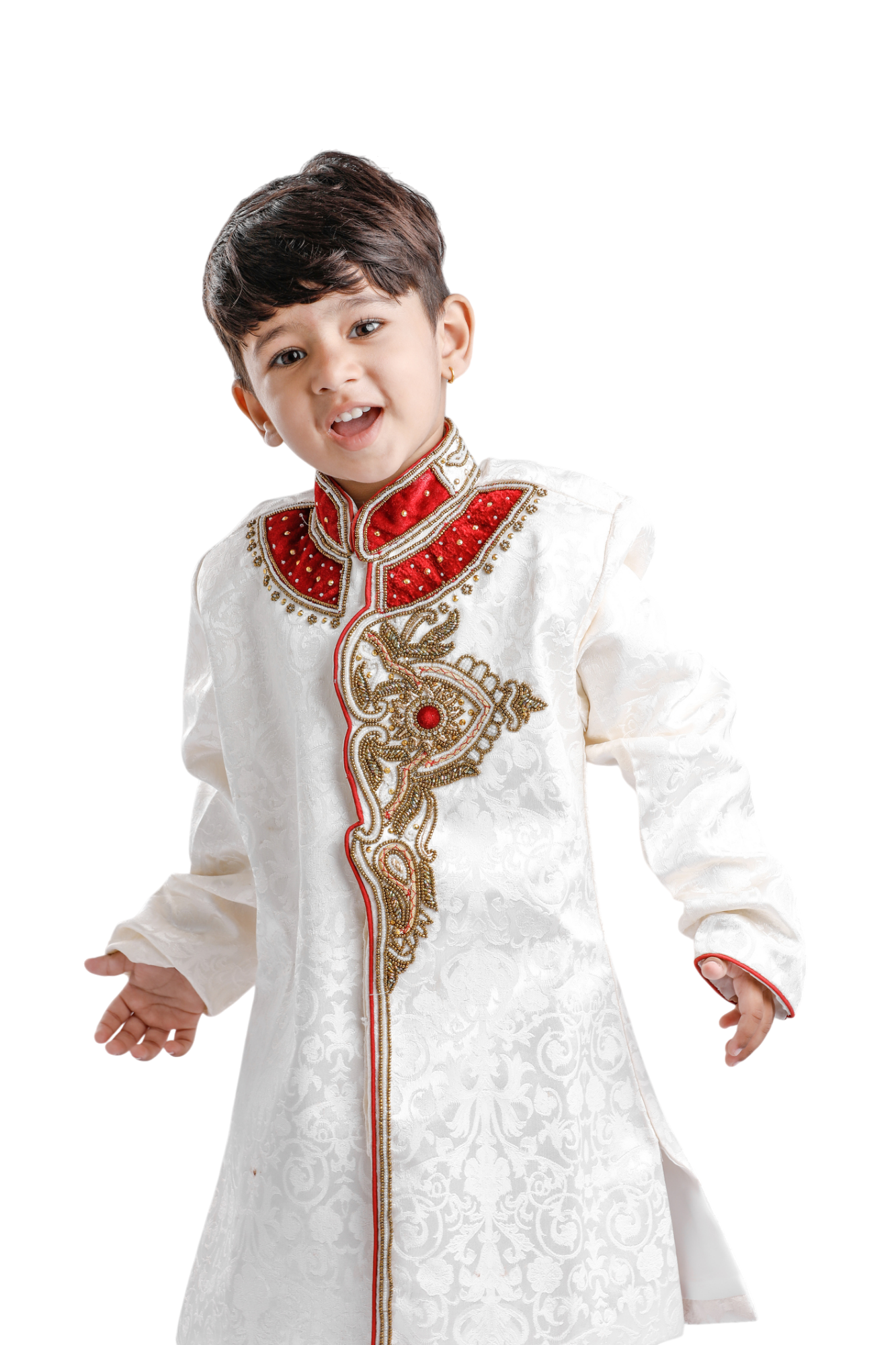 Young boy in traditional cream-colored Indian formal wear, smiling with open arms. Red and gold embroidery on the neckline and bodice.