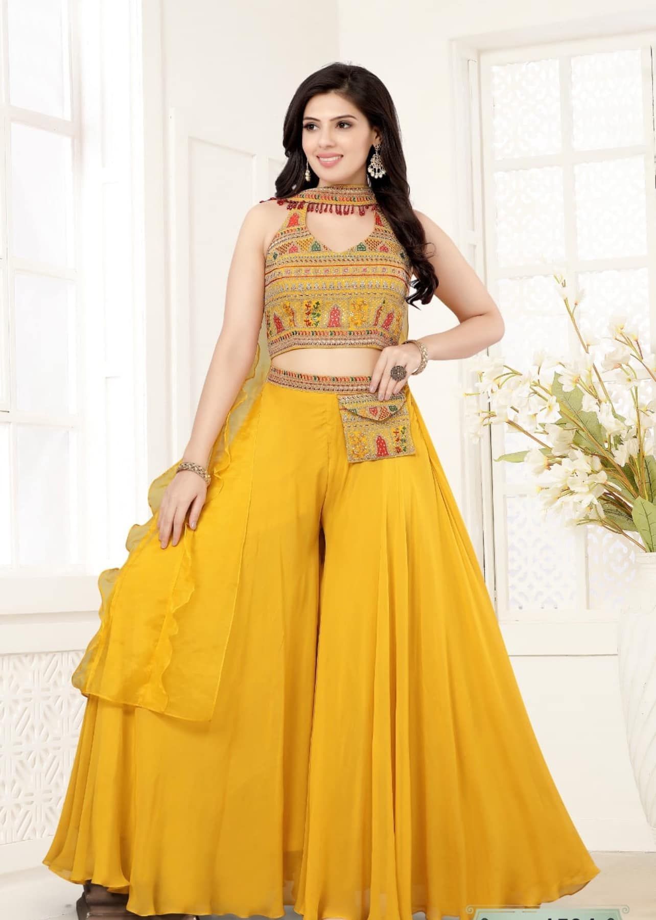 Woman in yellow ethnic outfit, smiling. She's wearing a crop top with palazzo pants.