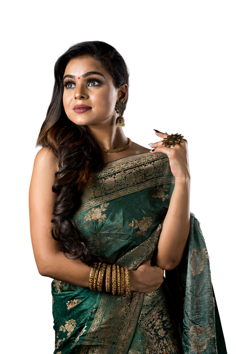 Woman in green and gold sari, looking up, with jewelry.