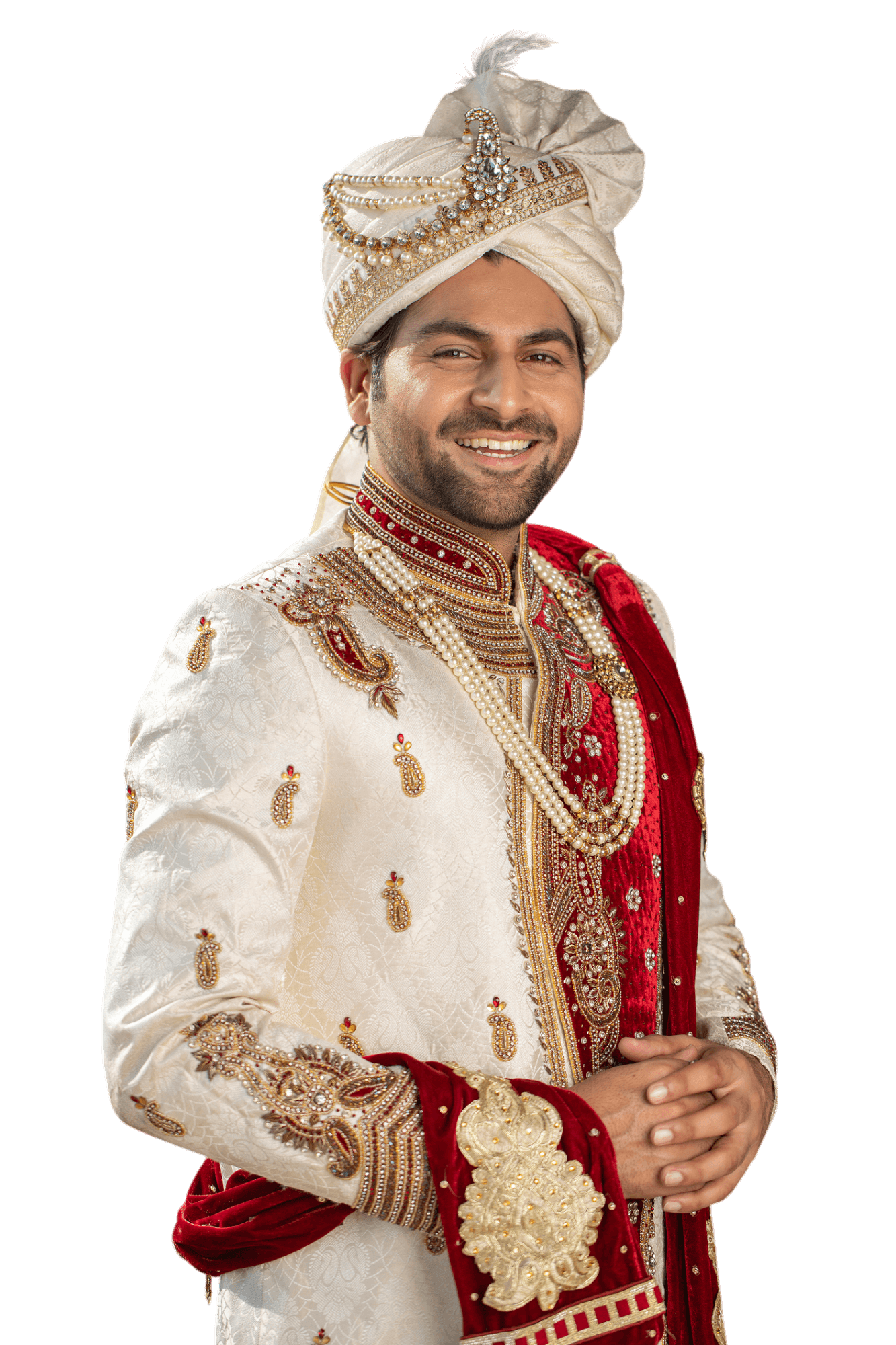 Man wearing ornate cream and gold wedding attire, including a turban and red accents, smiling.