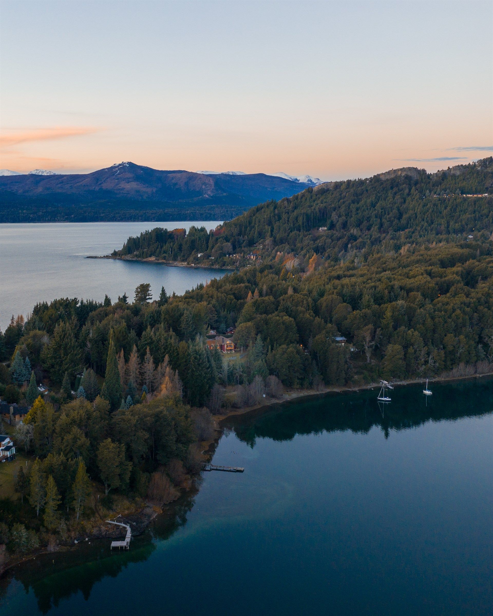 Una vista aérea de un lago rodeado de árboles y montañas.