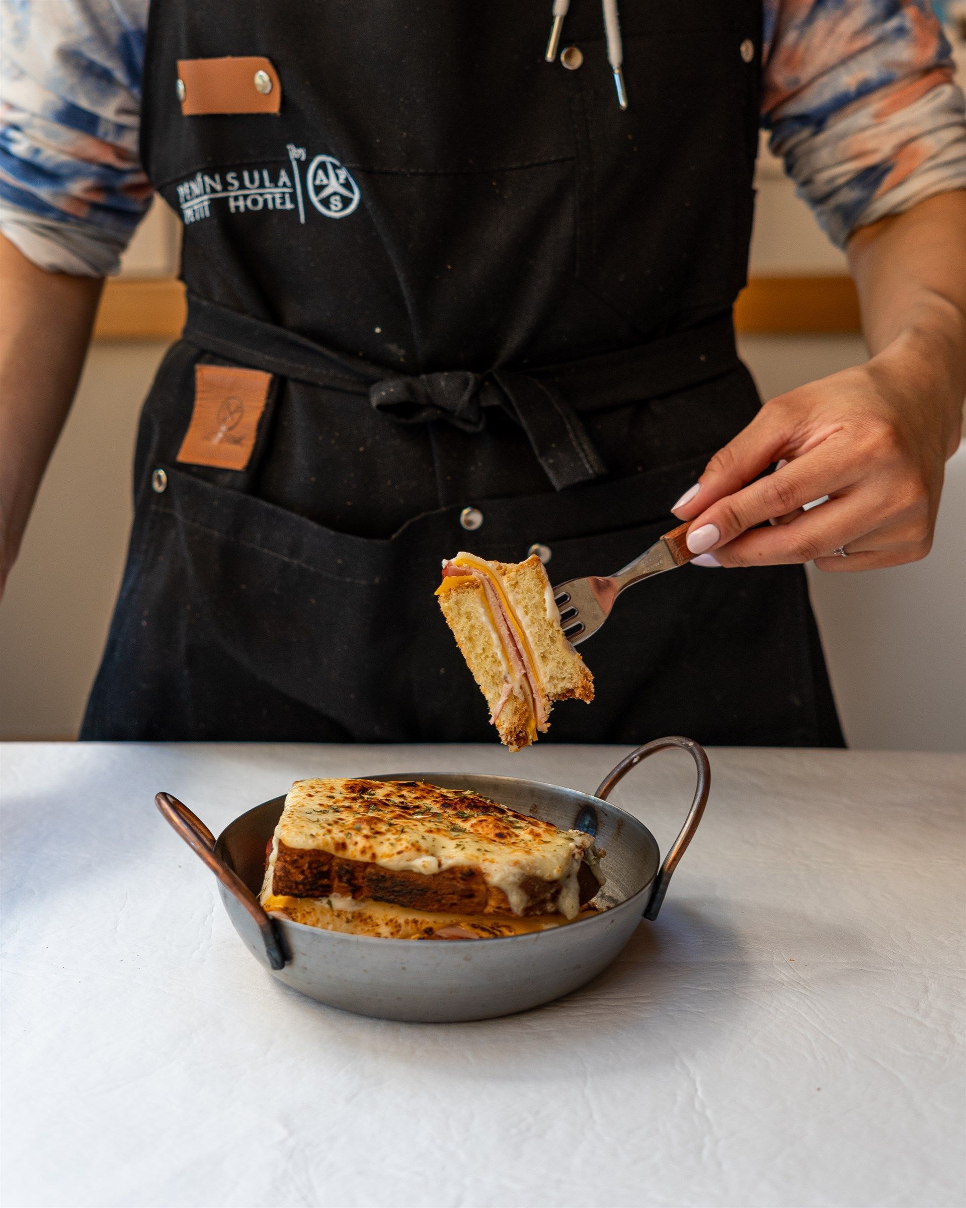 Un hombre con delantal sostiene un tenedor sobre un plato de comida.