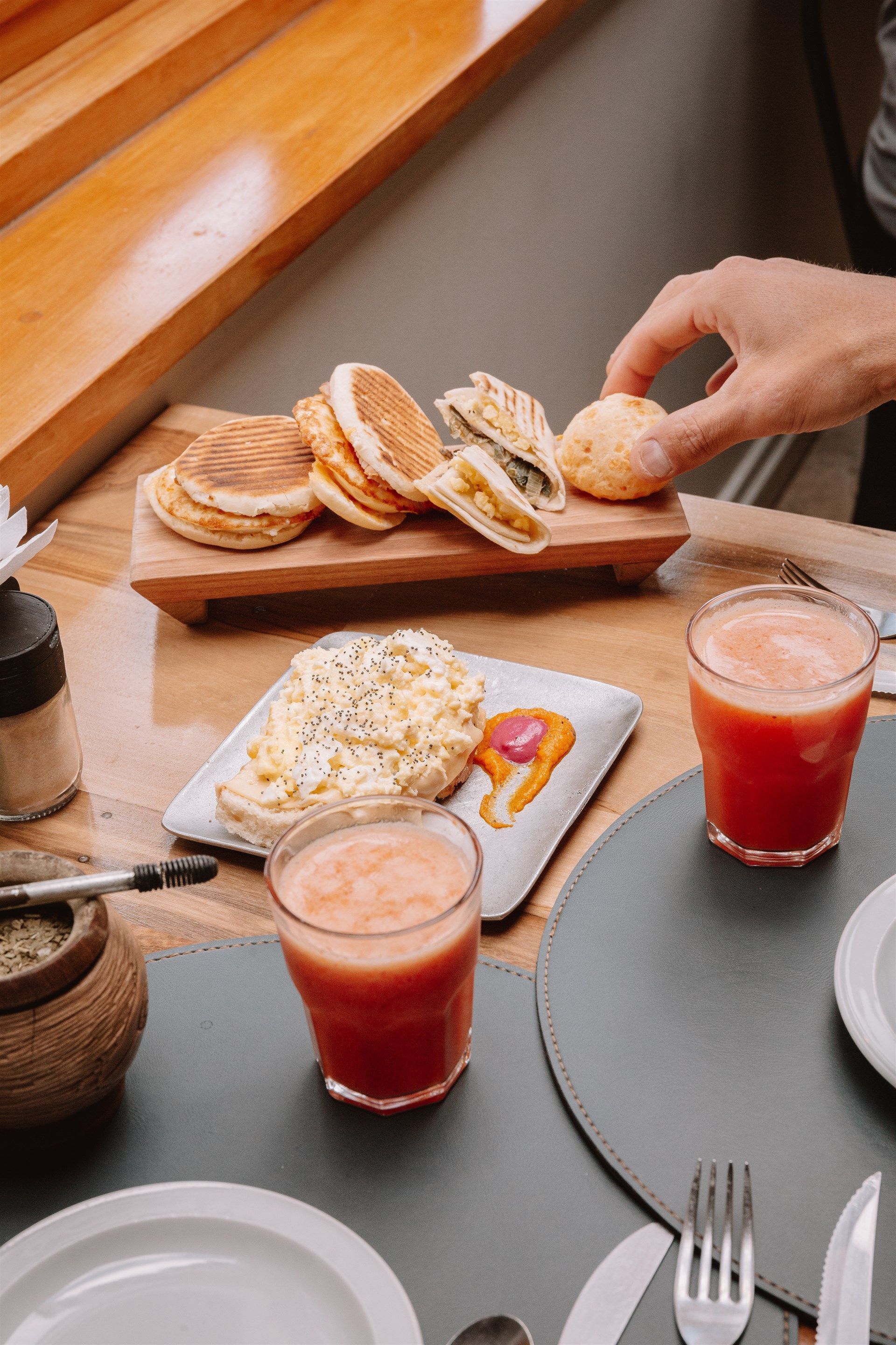 Una persona está tomando un trozo de comida de un plato sobre una mesa.