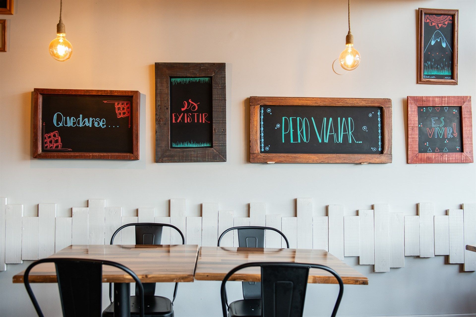 Un restaurante con mesas y sillas y pizarrones en la pared.