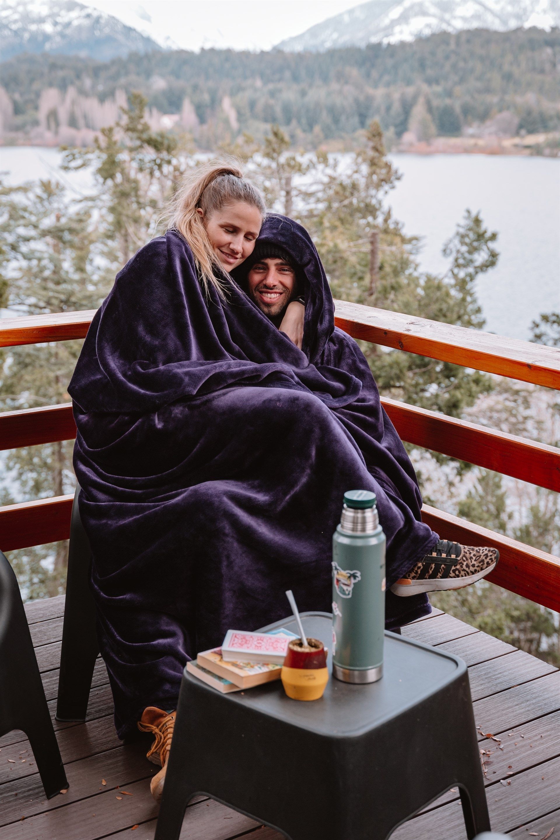 Un hombre y una mujer envueltos en una manta morada están sentados en una cubierta.