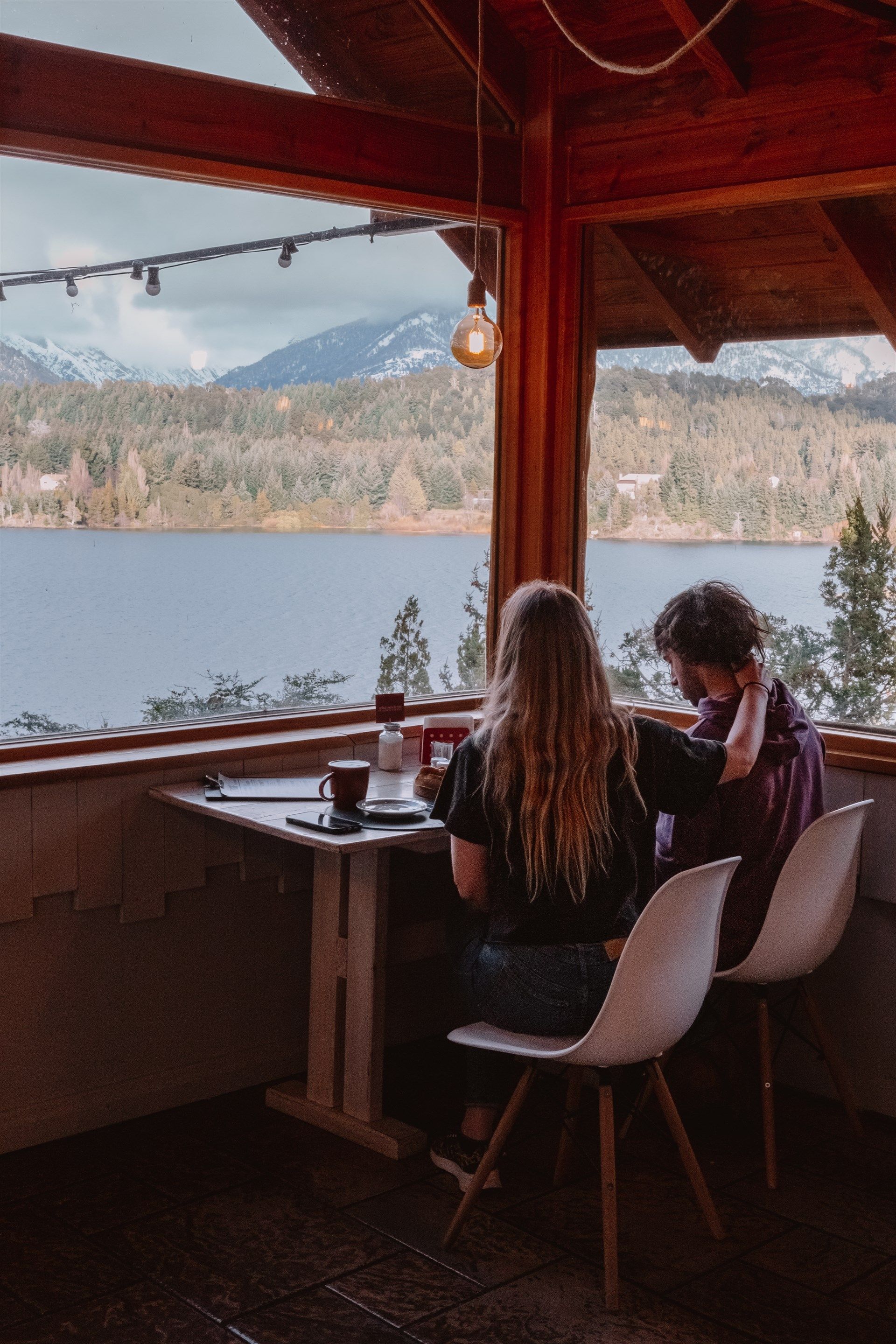 Un hombre y una mujer están sentados en una mesa con vista a un lago.