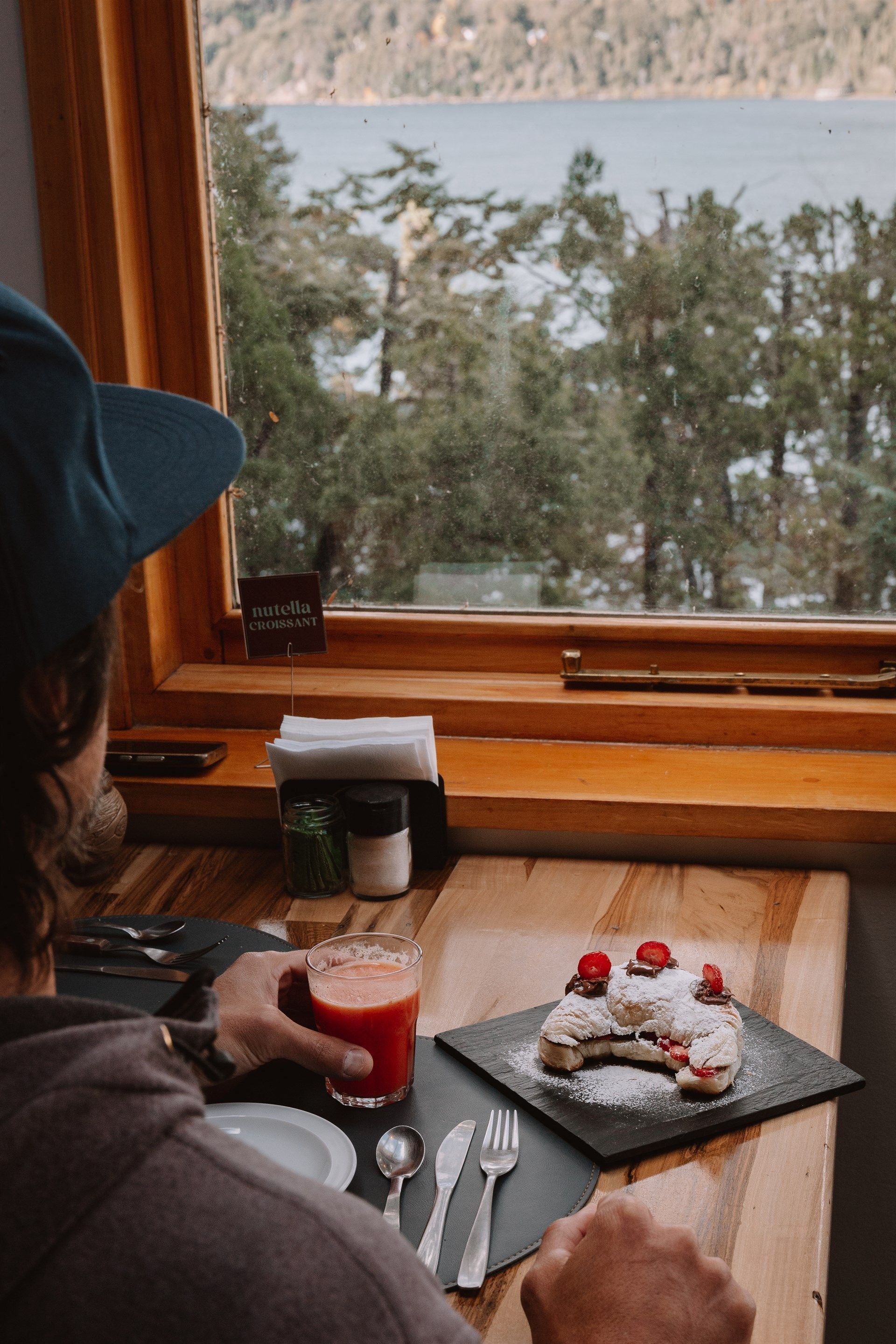 Un hombre está sentado en una mesa con un plato de comida y un vaso de jugo de naranja.