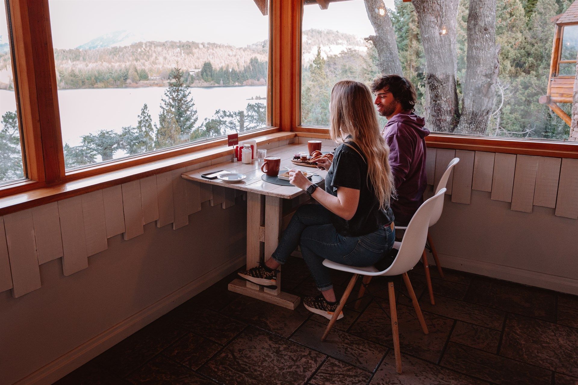 Un hombre y una mujer están sentados en una mesa frente a una ventana.