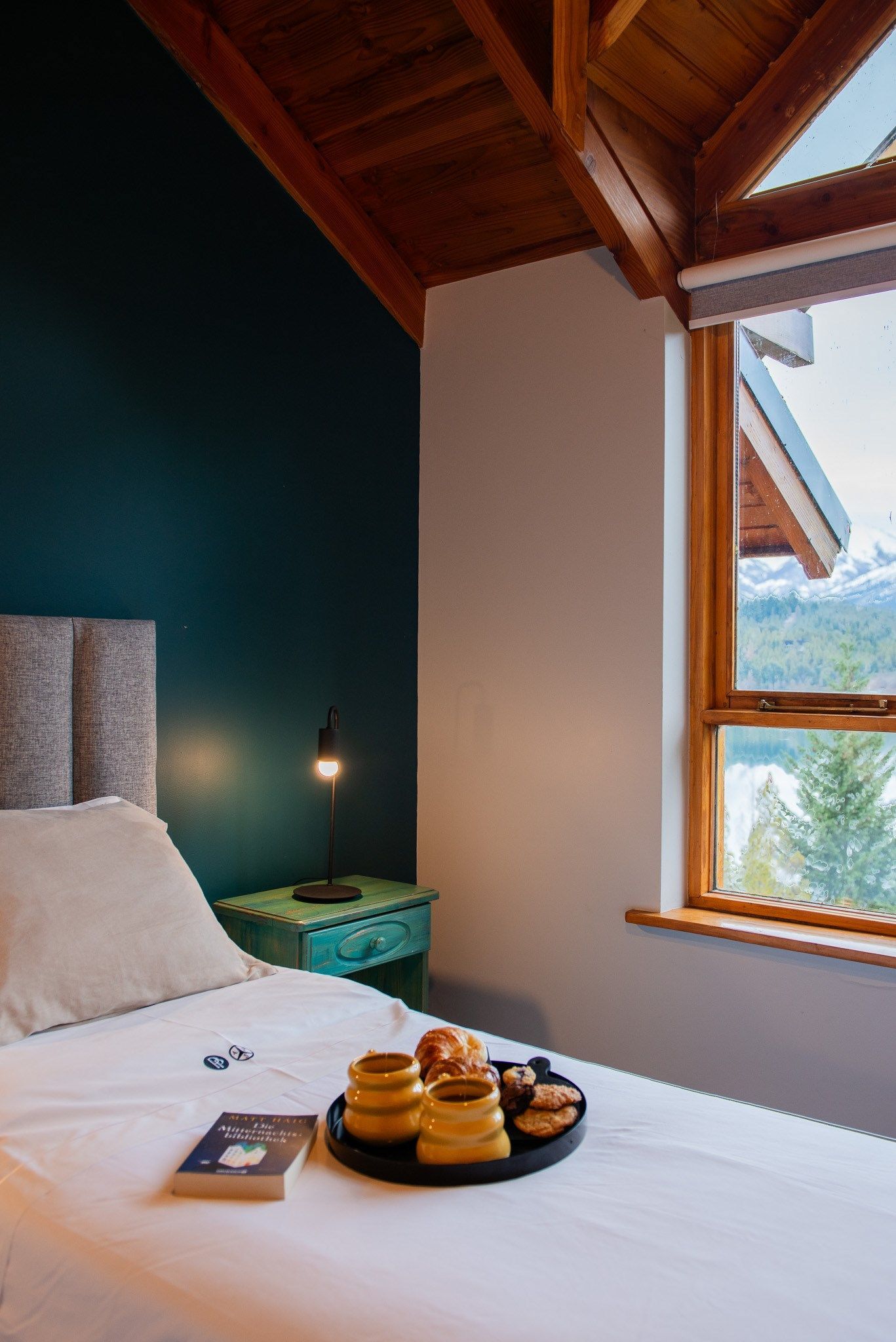 Una cama con una bandeja de comida y un libro encima en un dormitorio.