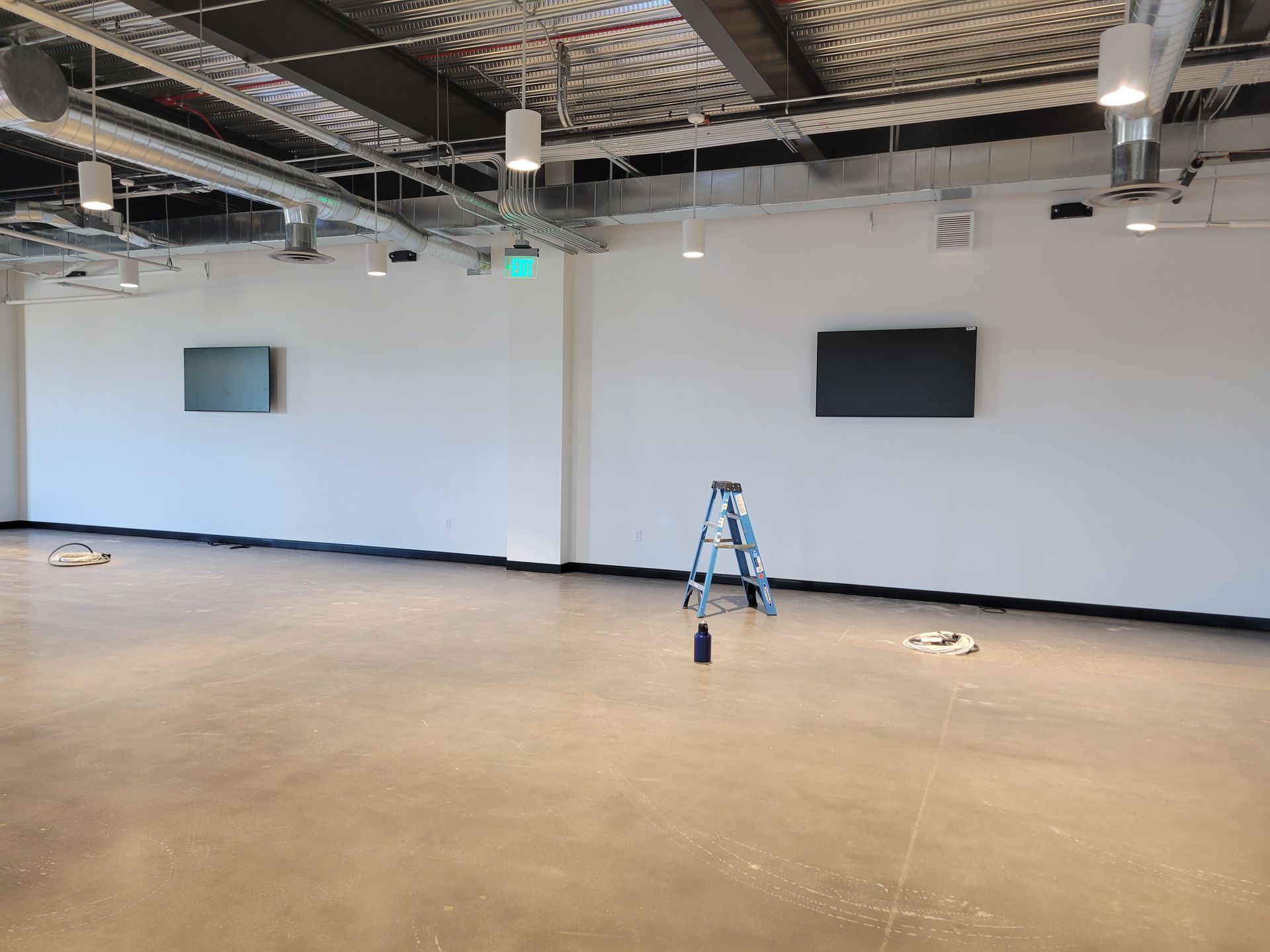 An empty room with a ladder and a television on the wall.
