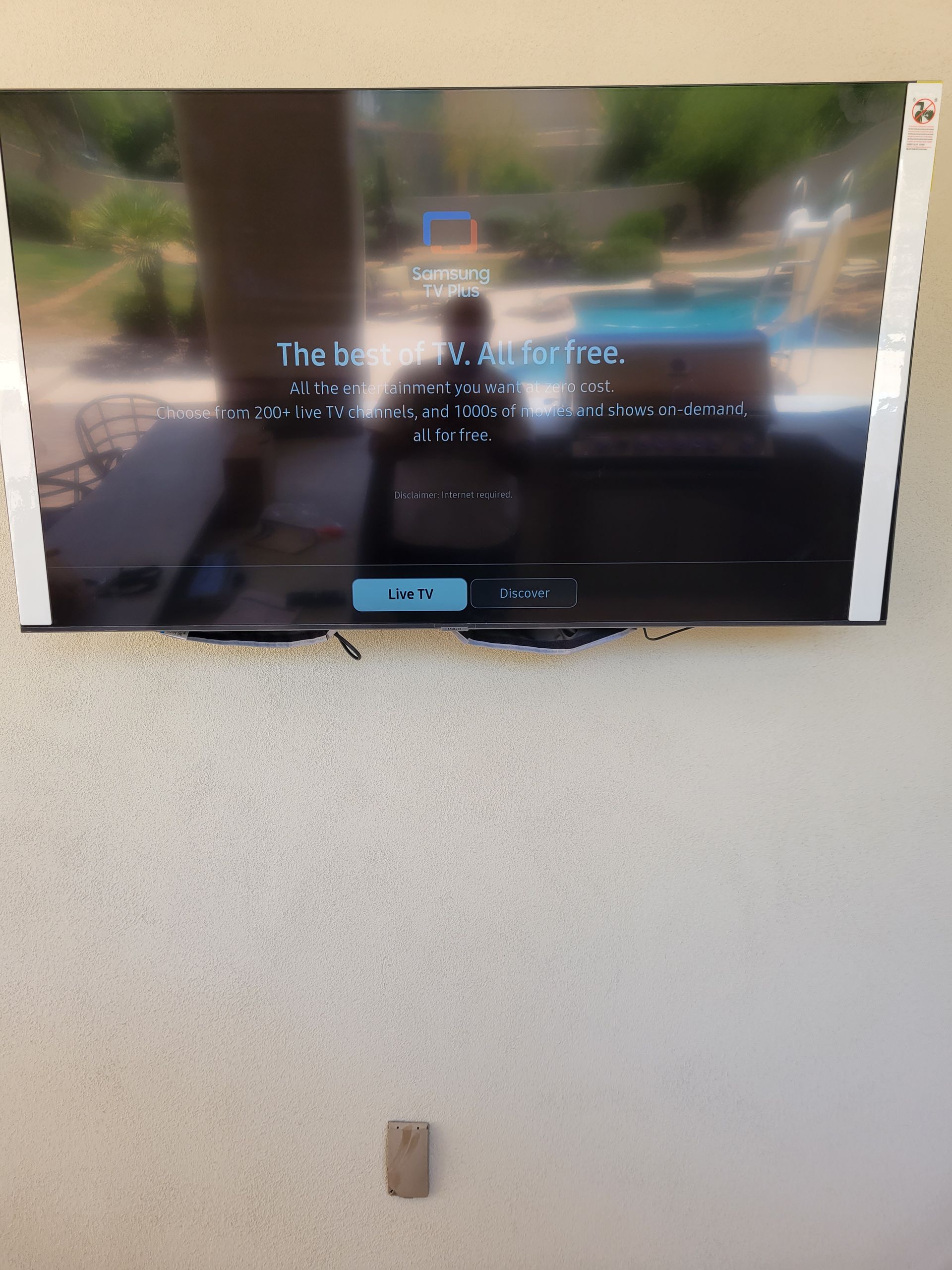 A flat screen tv is mounted on a wall and shows a picture of a pool