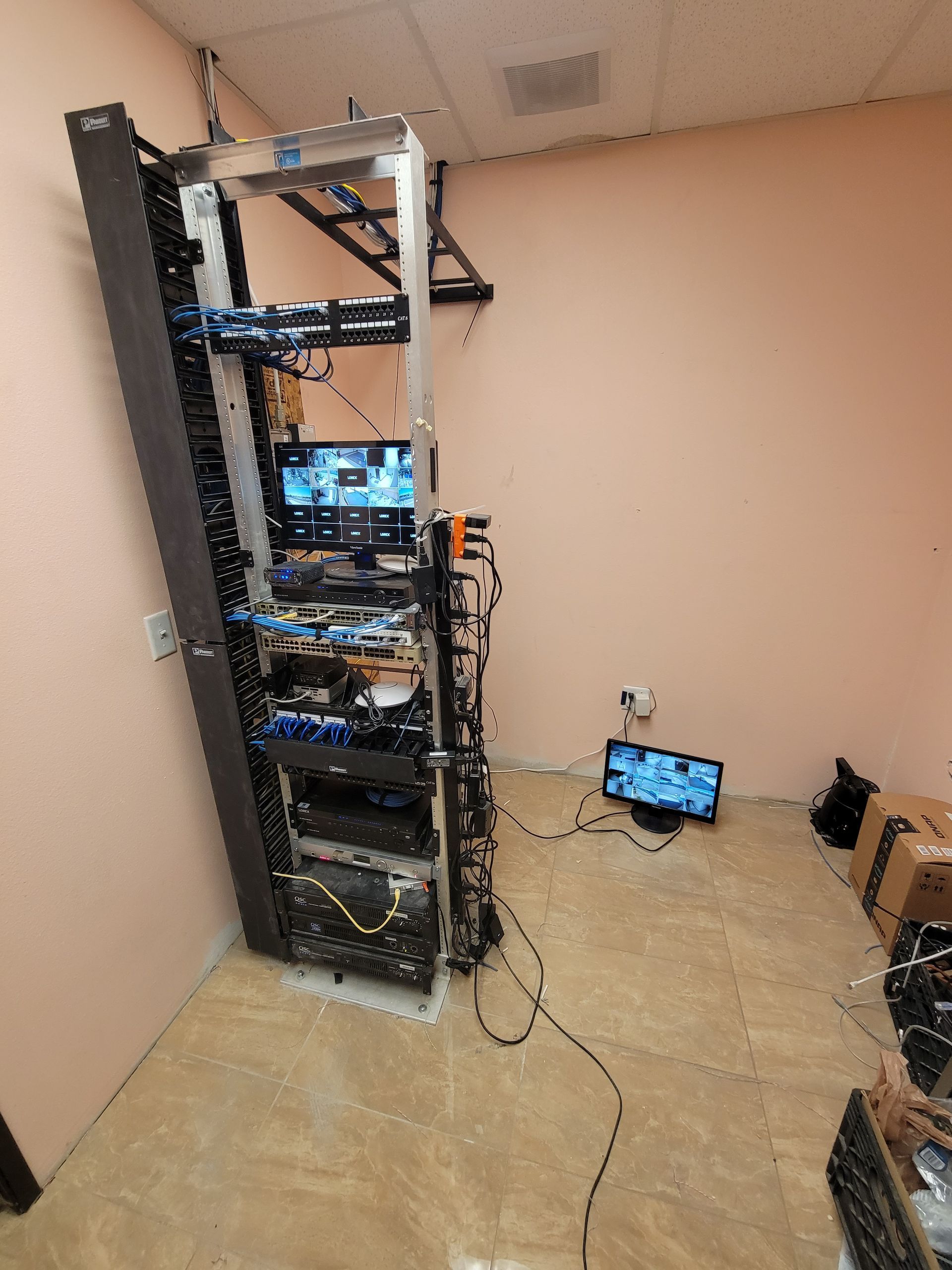 A room with a lot of computer equipment and a tv on the floor.