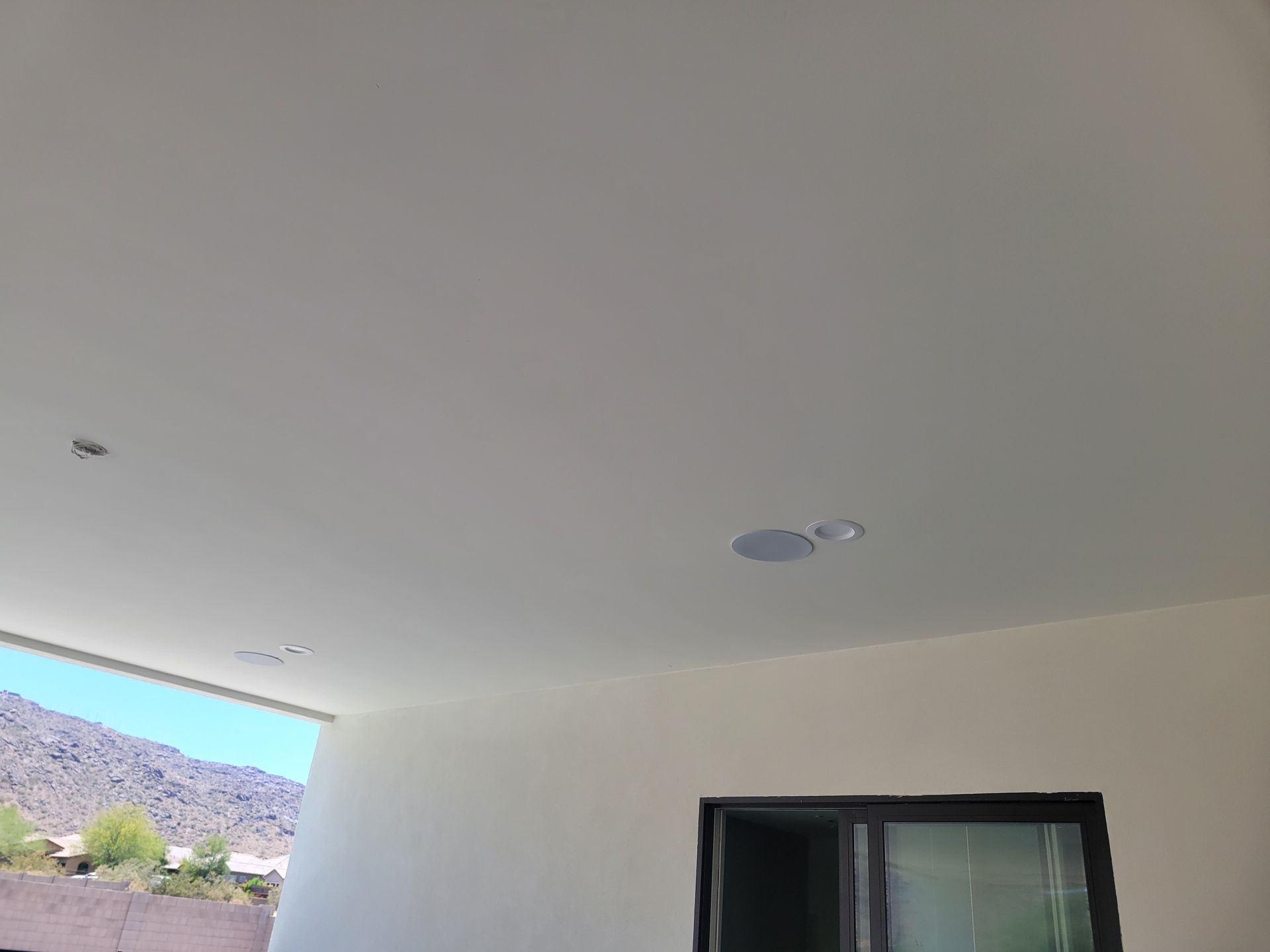 The ceiling of a room with a window and mountains in the background