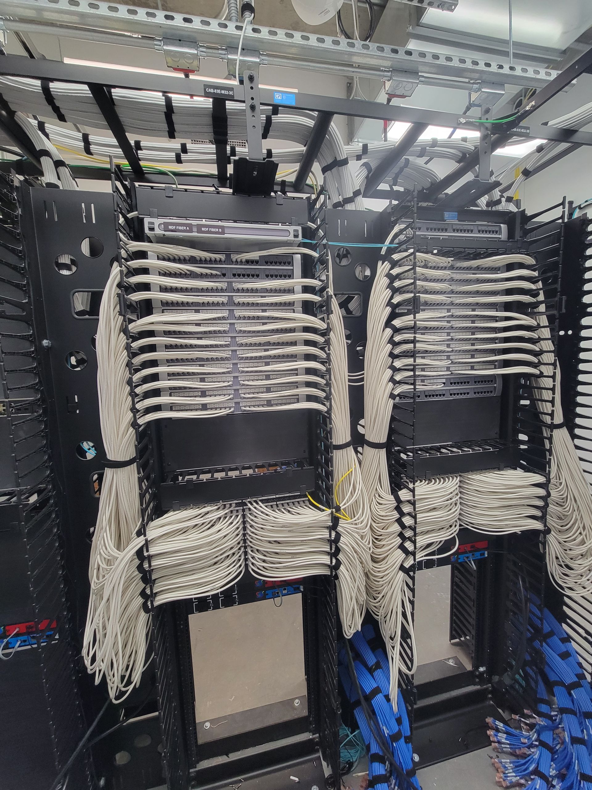 A server room with a lot of wires hanging from the ceiling.
