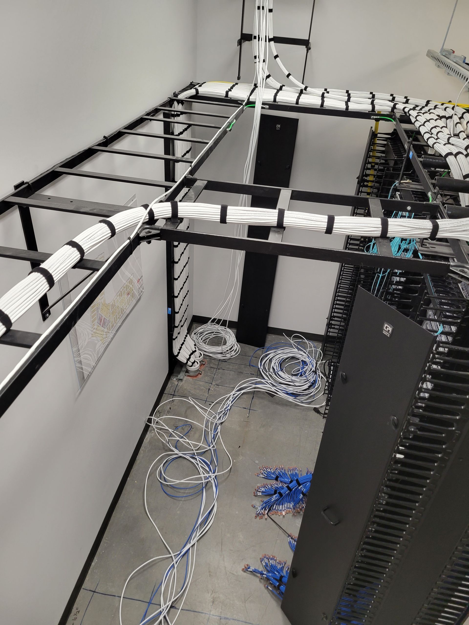 A room with a lot of wires hanging from the ceiling and a ladder.