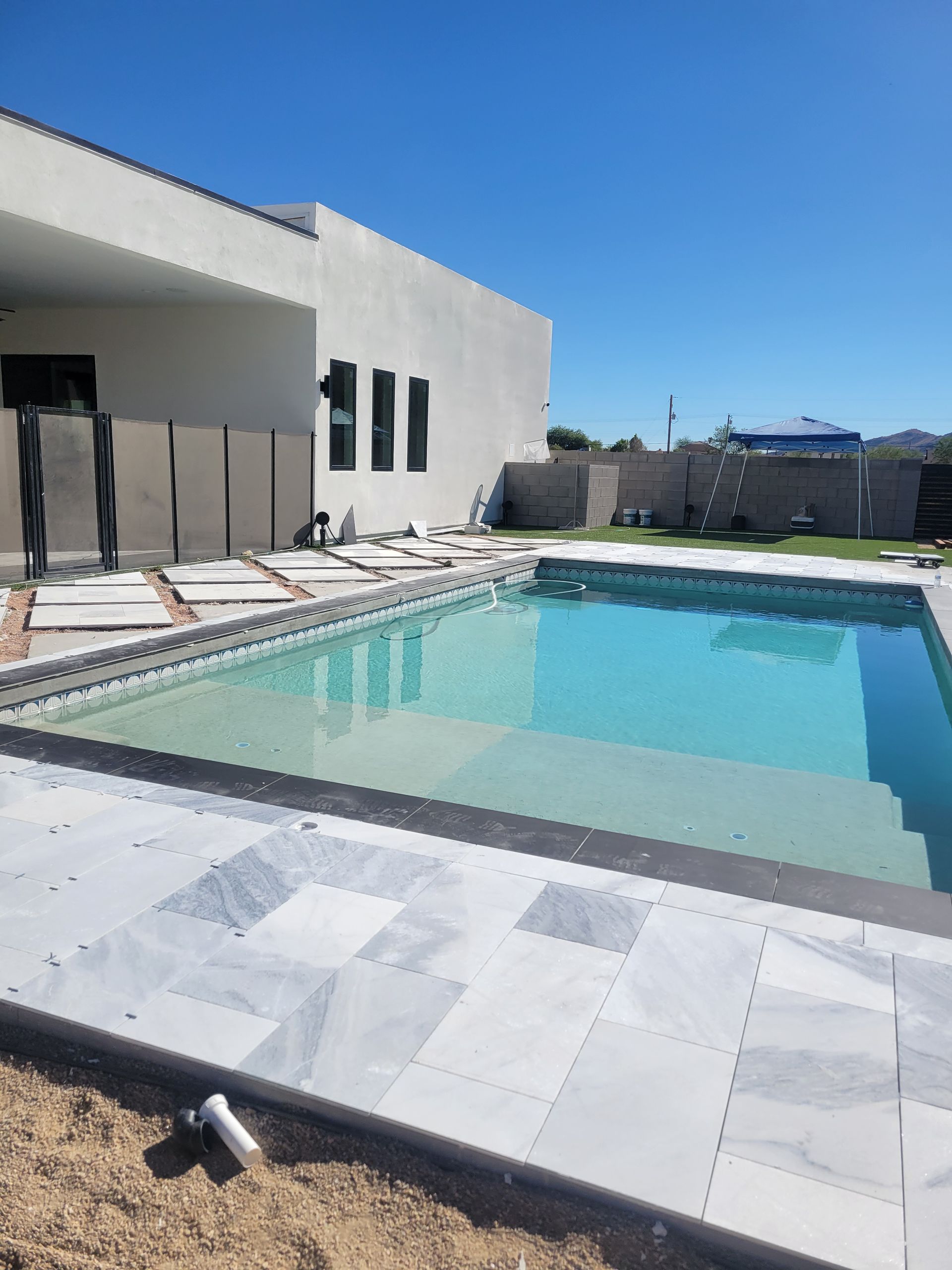 A large swimming pool is in the backyard of a house.