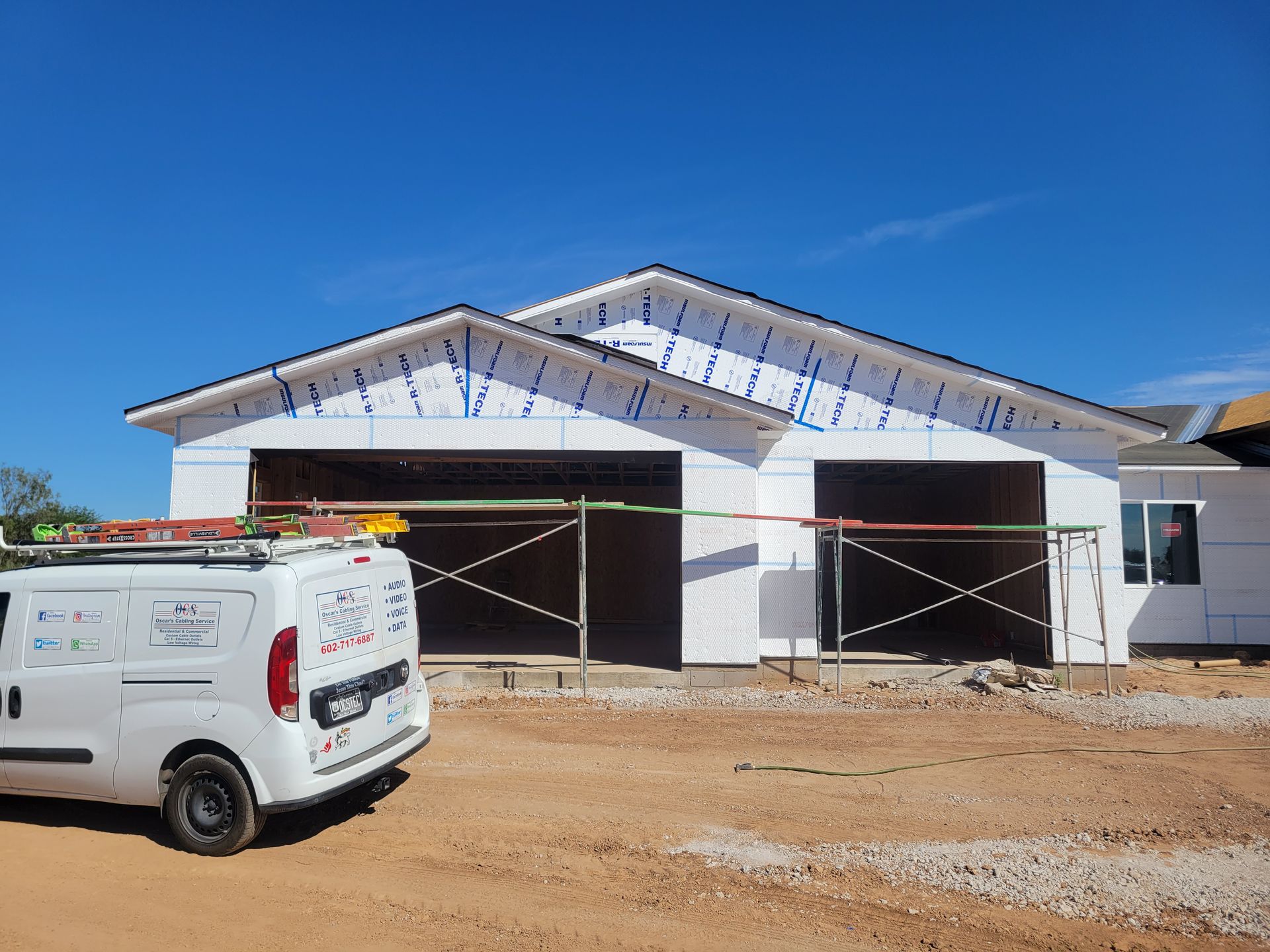 A white van is parked in front of a house under construction.