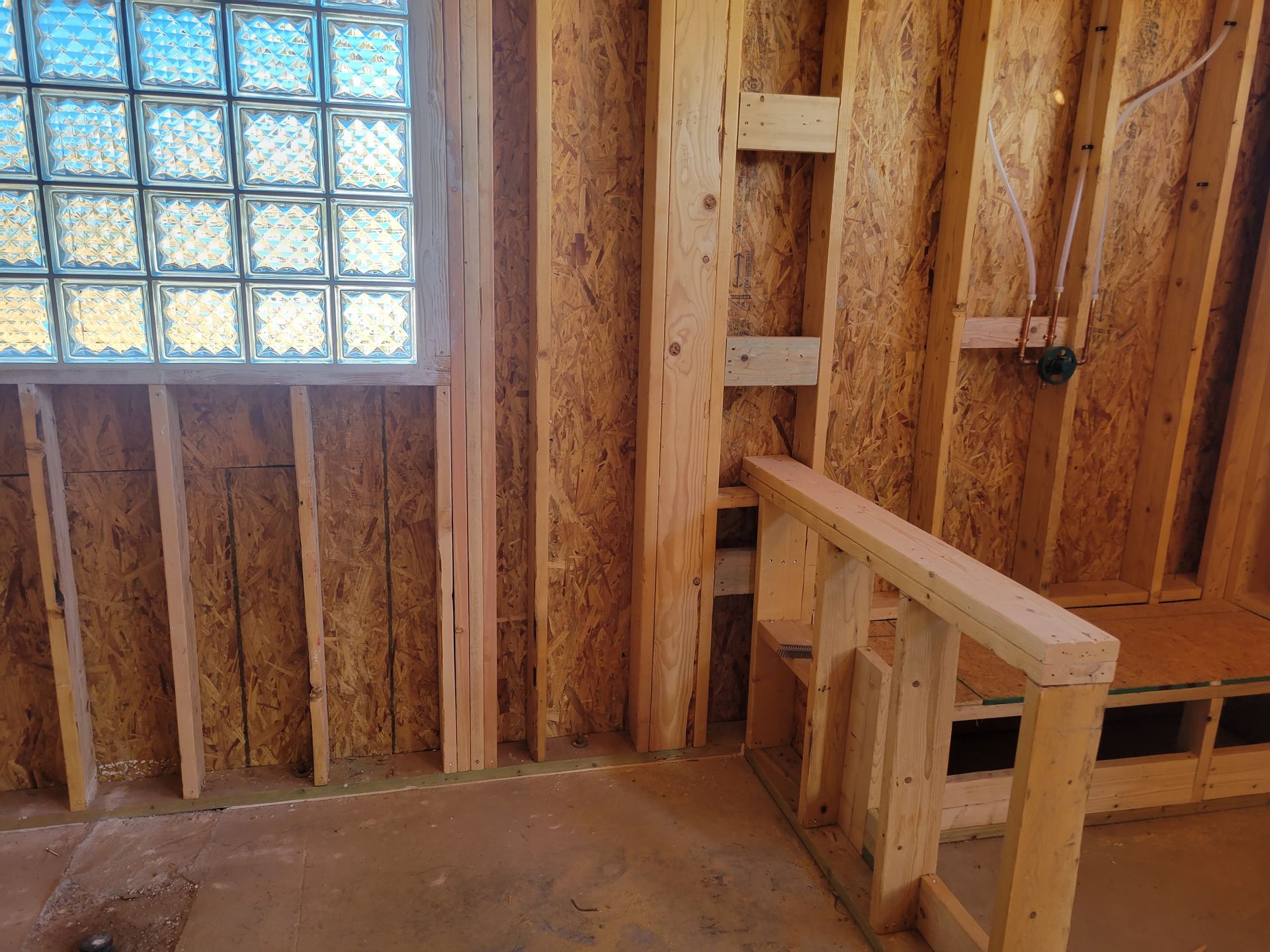 A wooden wall with a window and stairs in a house under construction.