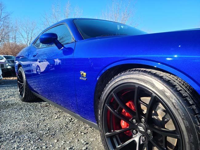 Blue Dodge Challenger with black rims and red brake calipers.