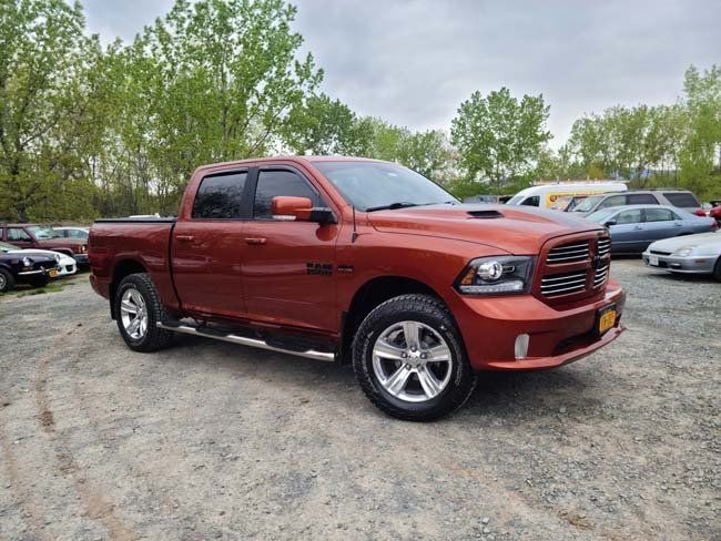 Orange Dodge Ram pickup truck in a gravel lot.