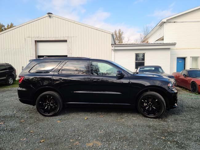Black Dodge Durango SUV parked outside a white building on a gravel lot.