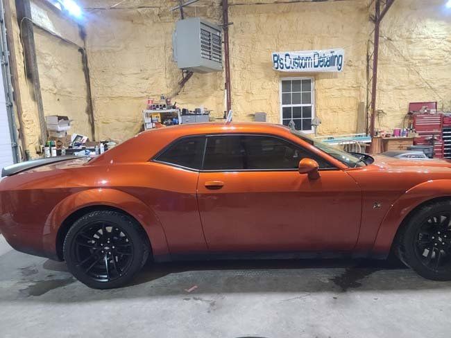 Orange Dodge Challenger in a garage.