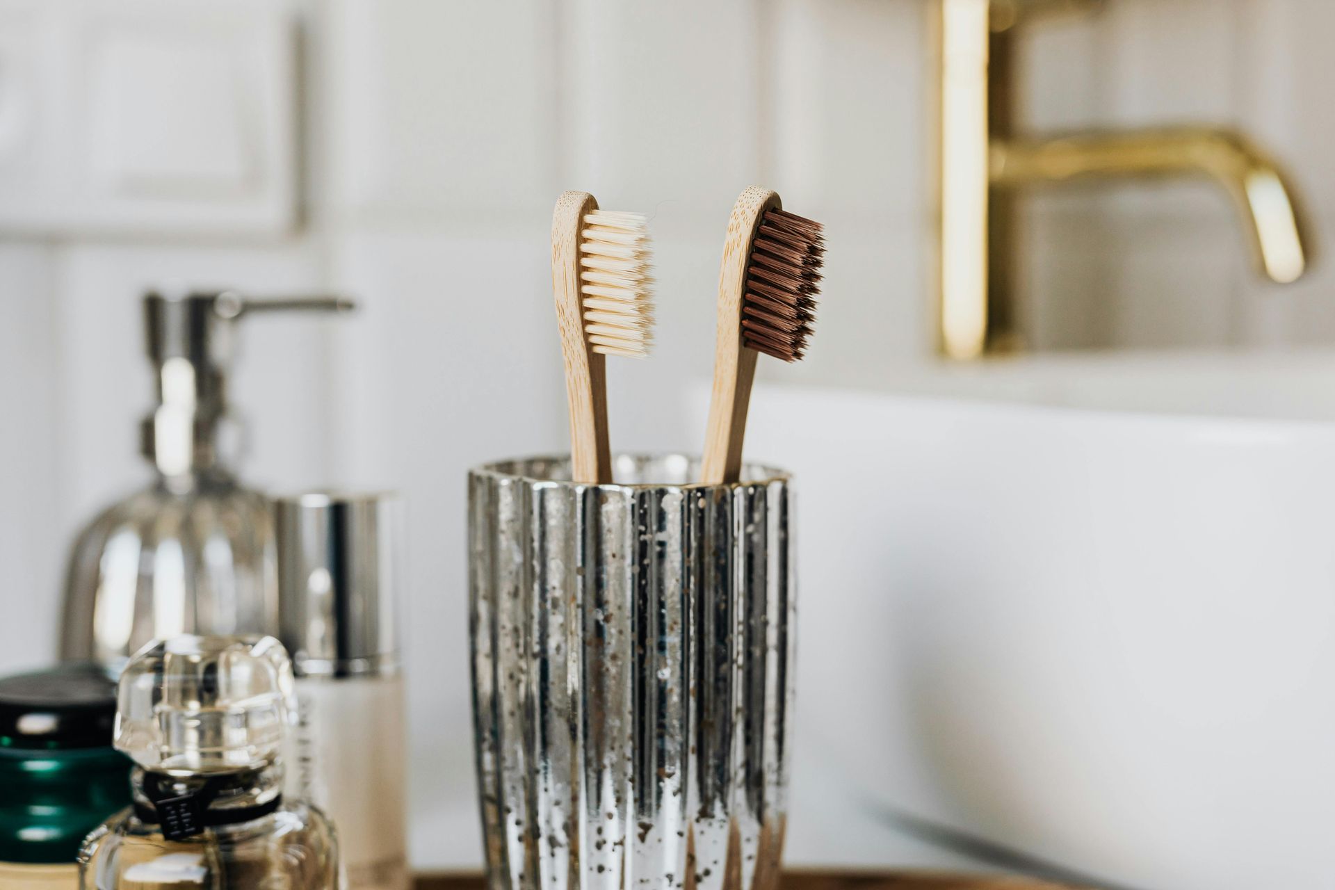Two wooden toothbrushes are sitting in a glass in a bathroom.