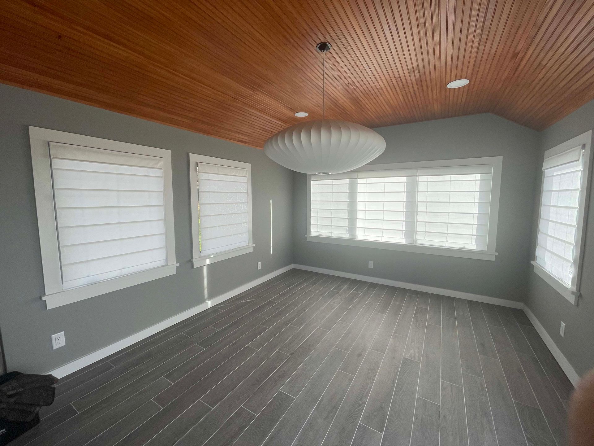 A large empty room with a wooden ceiling and lots of windows.