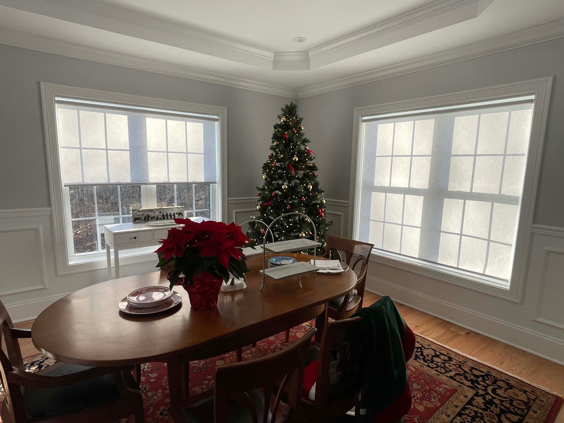 A dining room with a table and chairs and a christmas tree in the corner.